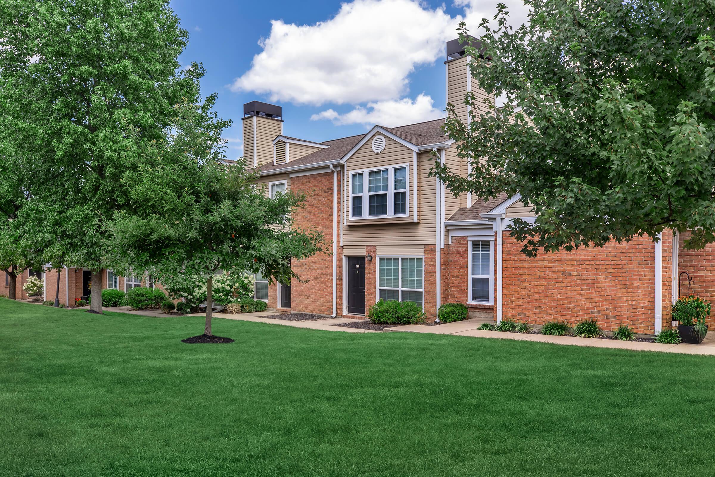 a large brick building with green grass in front of a house