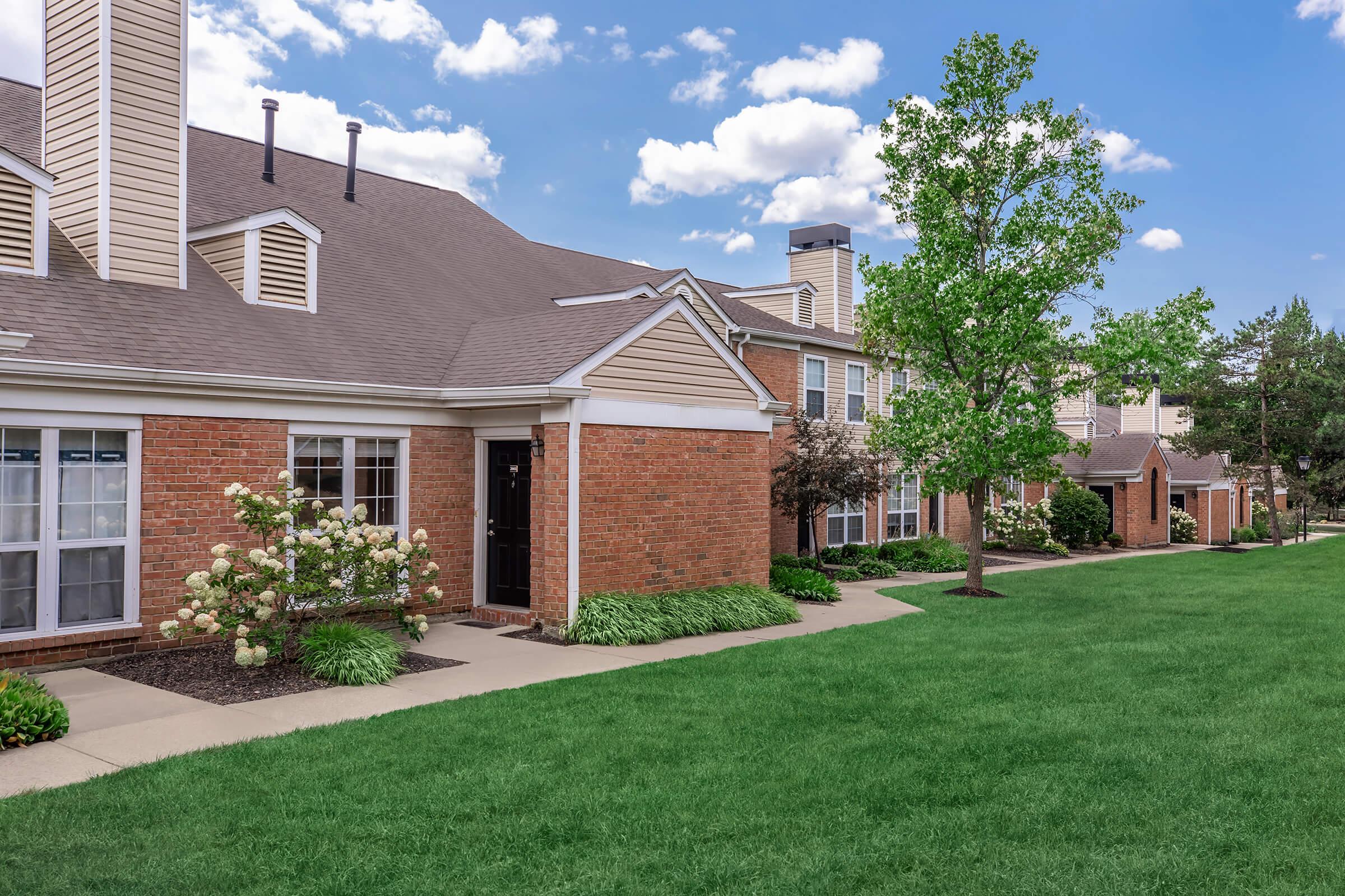 a large brick building with grass in front of a house