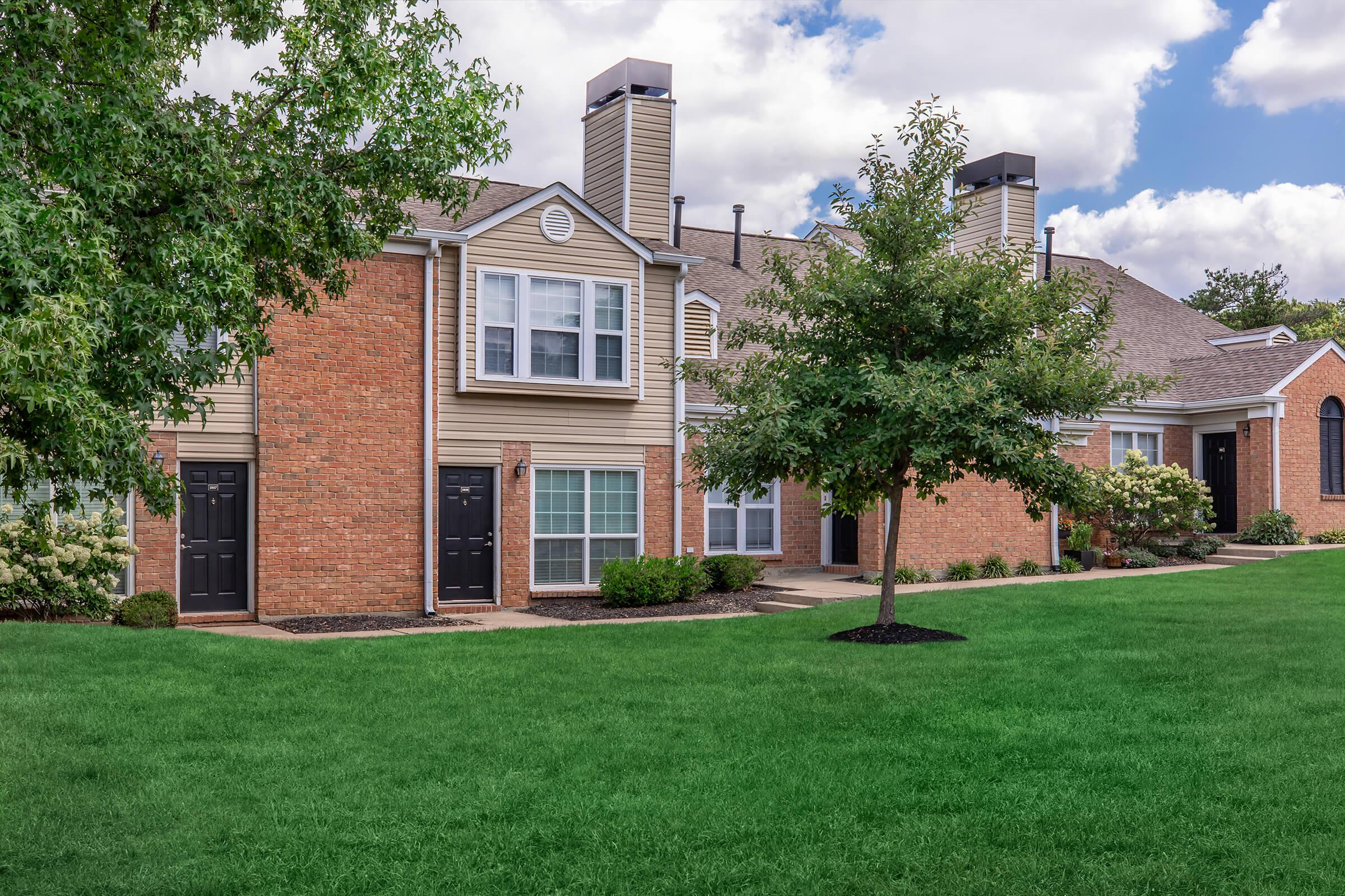 a large brick building with grass in front of a house