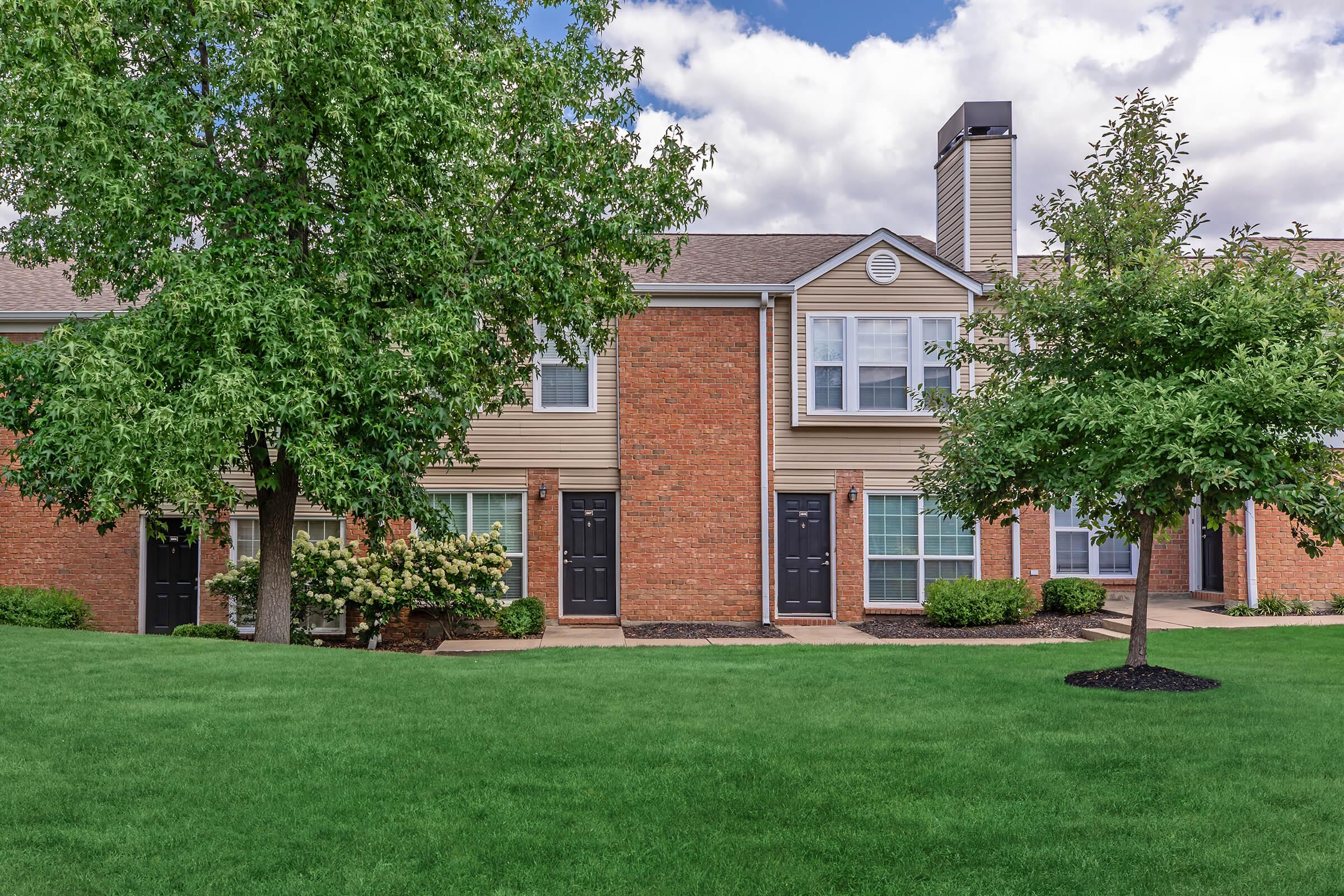 a large brick building with green grass in front of a house