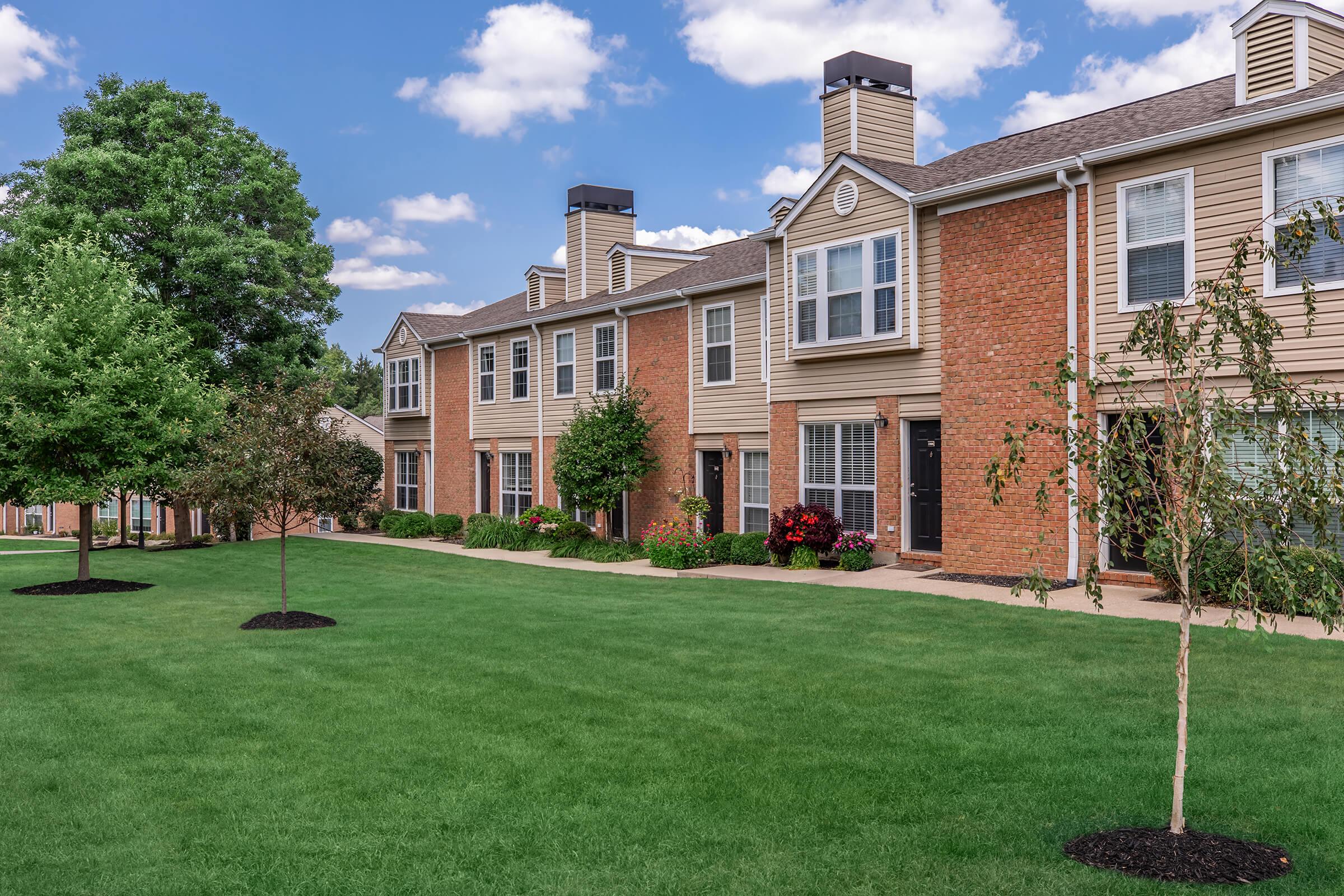 a large brick building with grass in front of a house