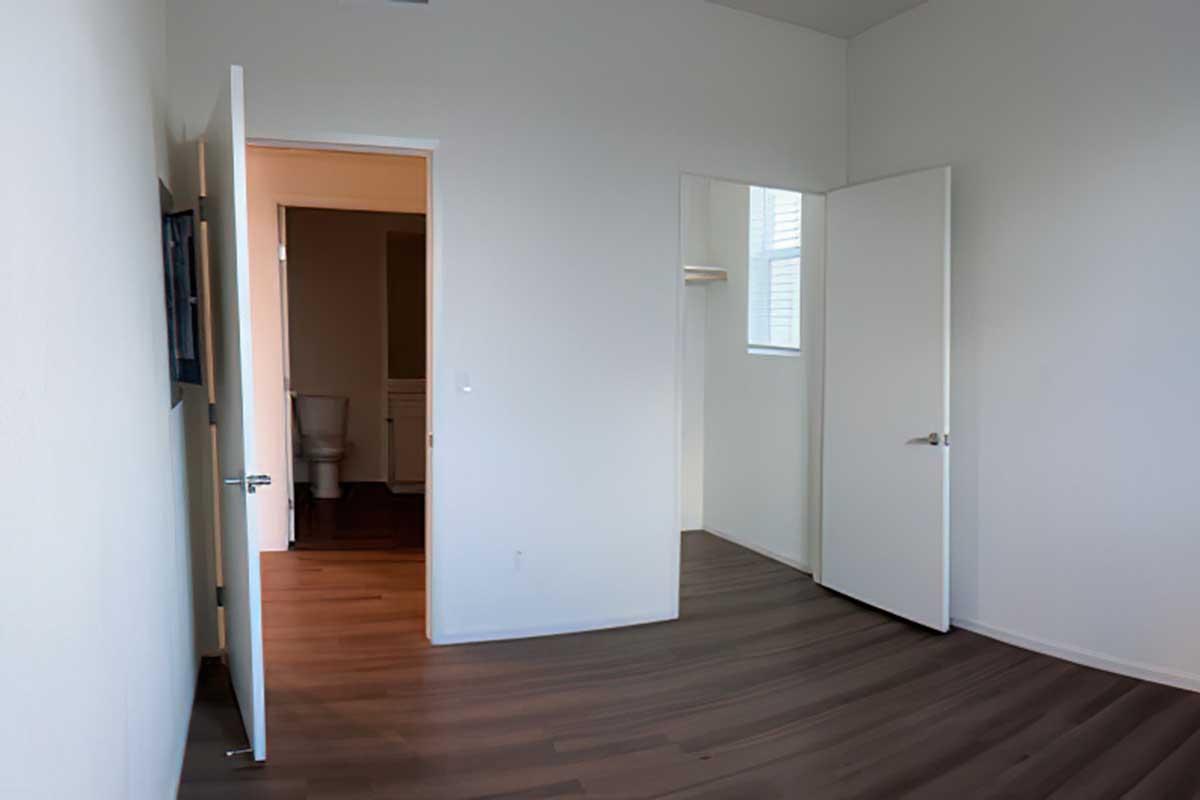 A partially furnished room with light-colored walls and wooden flooring.