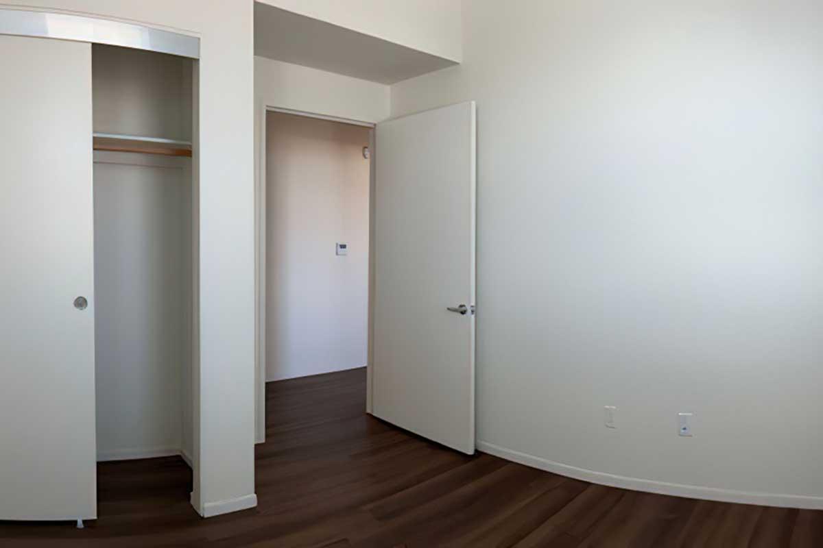 A small, empty room with light-colored walls and dark wooden flooring.