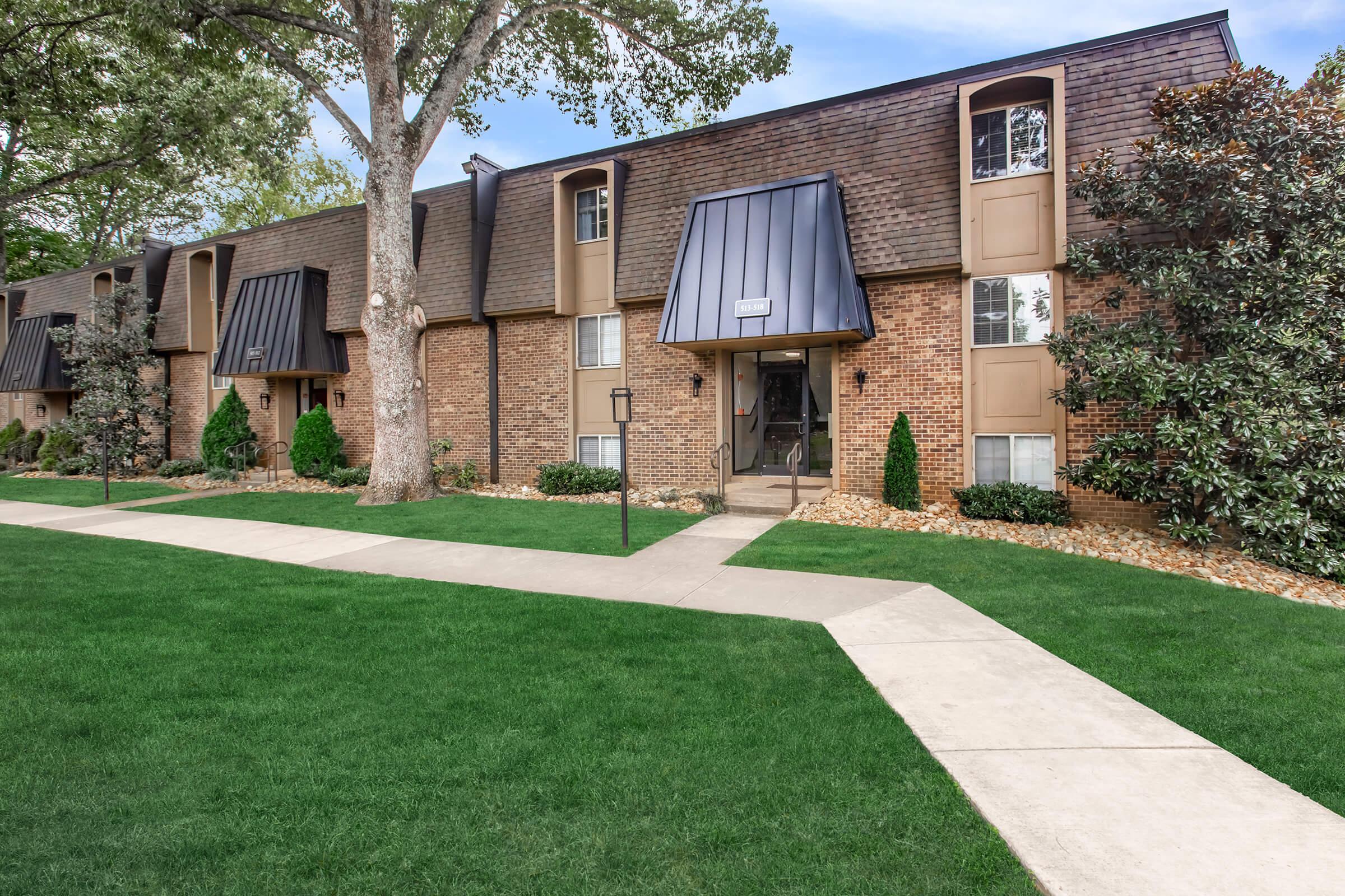 a house with a lawn in front of a brick building