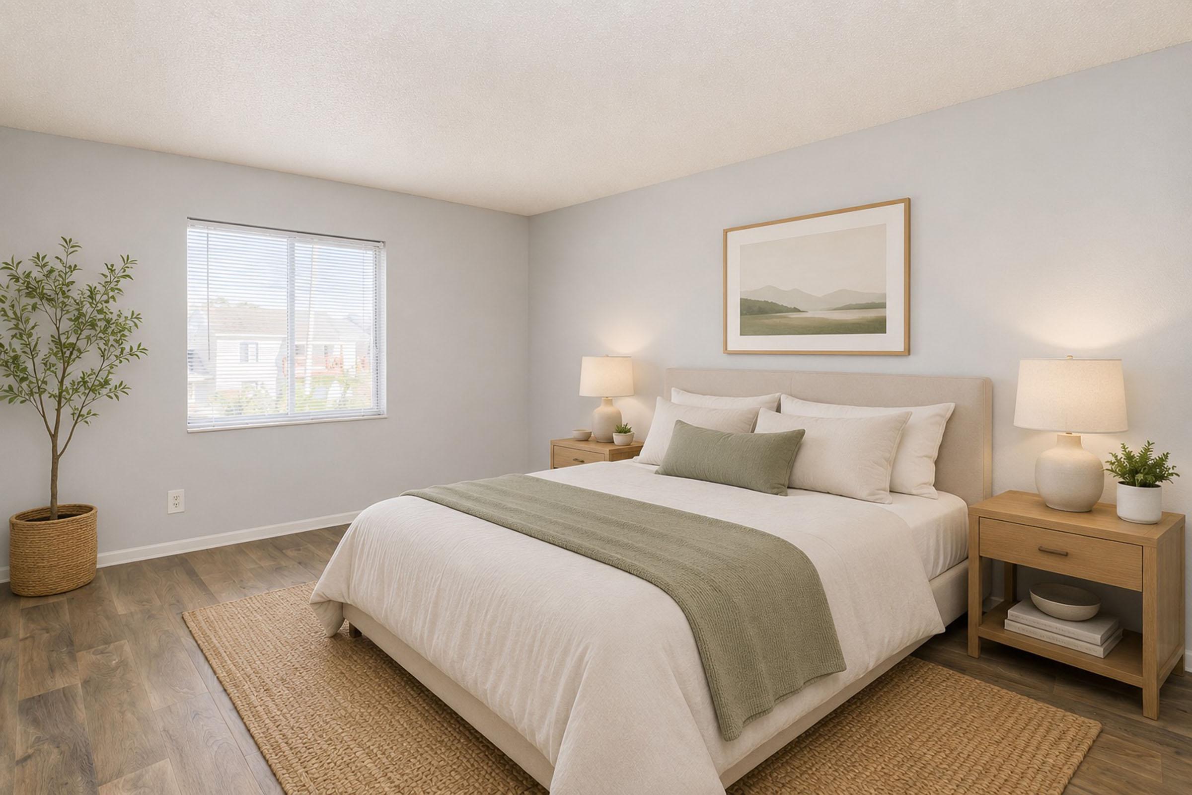 A modern, minimalist bedroom featuring a comfortable bed with white linens and a green throw blanket. Natural light streams in through a window, illuminating the space. Two bedside tables with lamps flank the bed, and a plant adds a touch of greenery. Soft, neutral tones create a serene atmosphere.