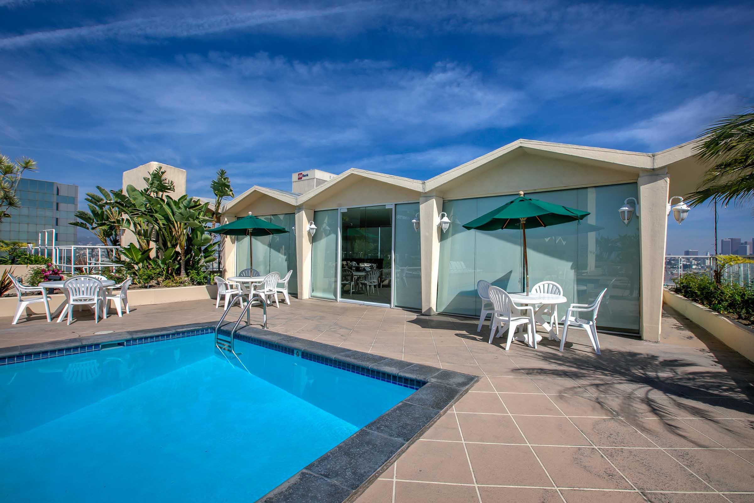 a pool next to a building and tables with umbrellas