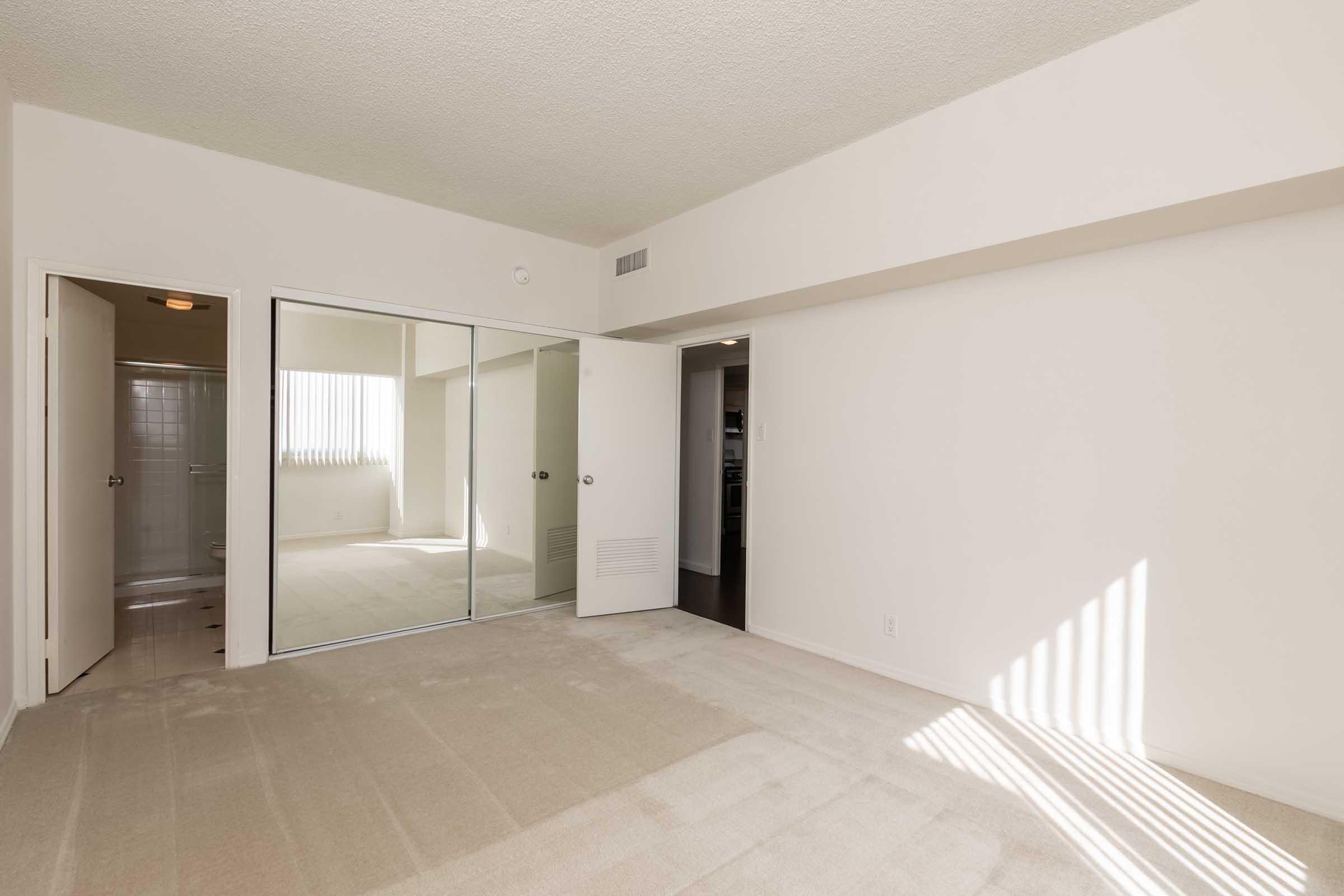 an empty bedroom with mirrored closet doors