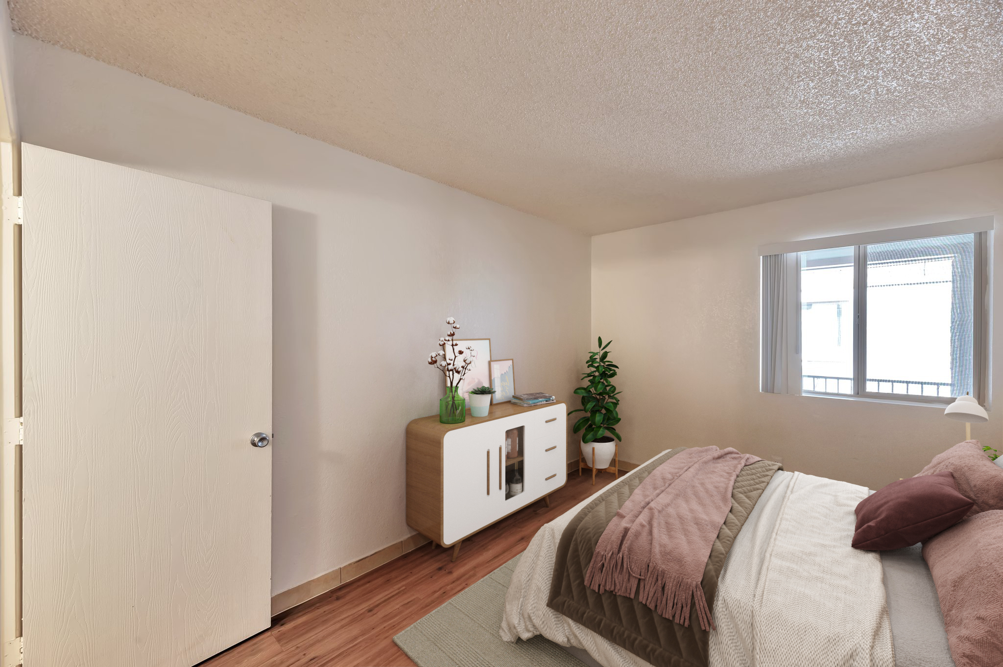 A cozy bedroom featuring a bed with layered blankets and pillows, a modern wooden nightstand, and a potted plant. A door is visible on the left, and a window allows natural light to brighten the space. The decor combines neutral tones and natural elements for a tranquil atmosphere.