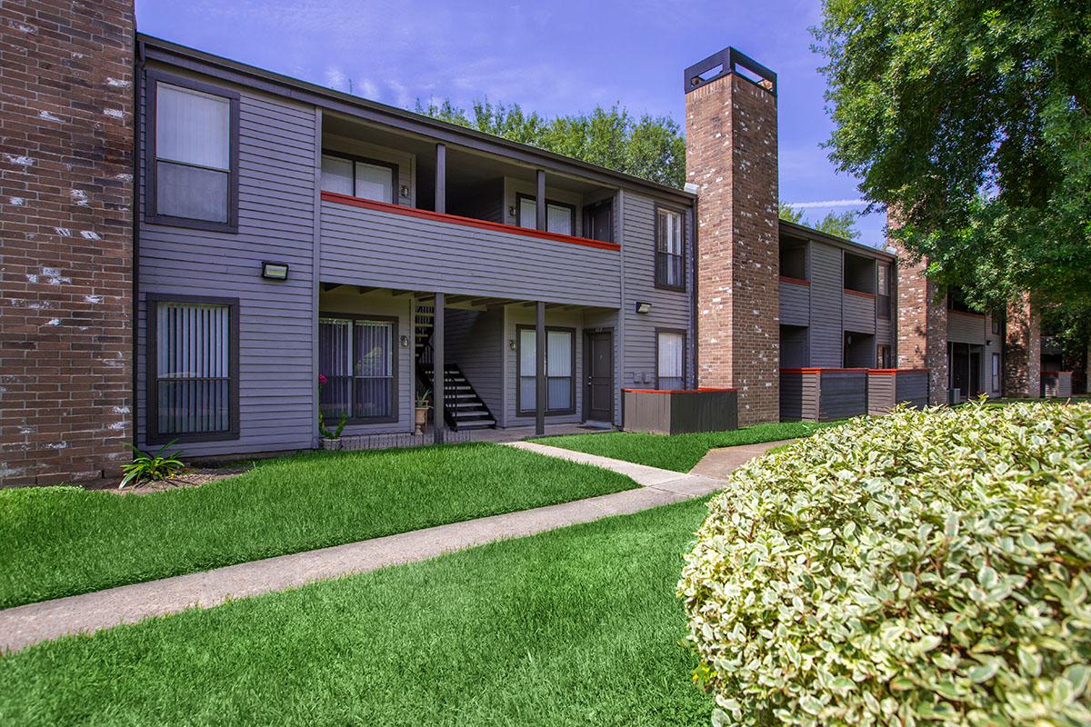 a house with a lawn in front of a brick building