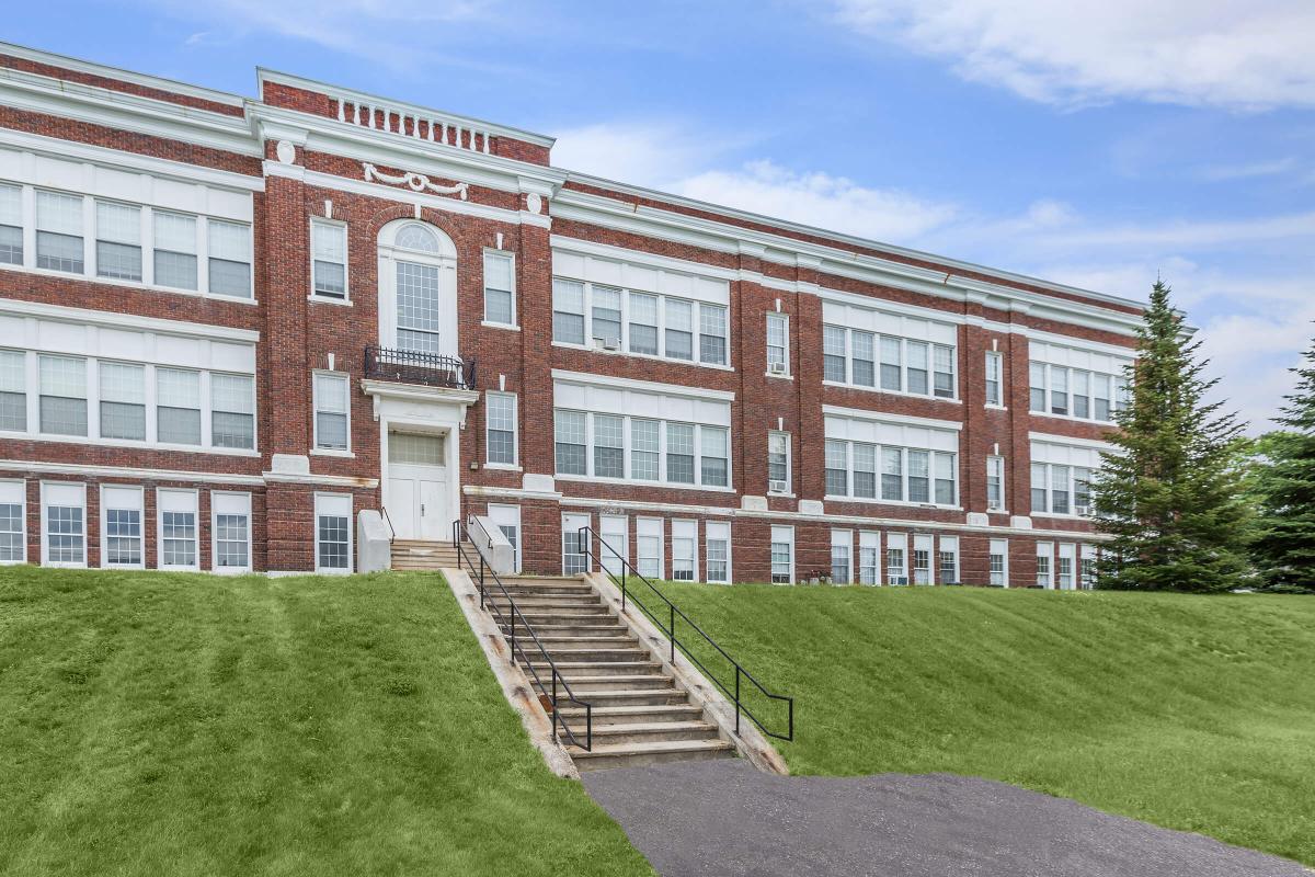 a large brick building with a grassy field