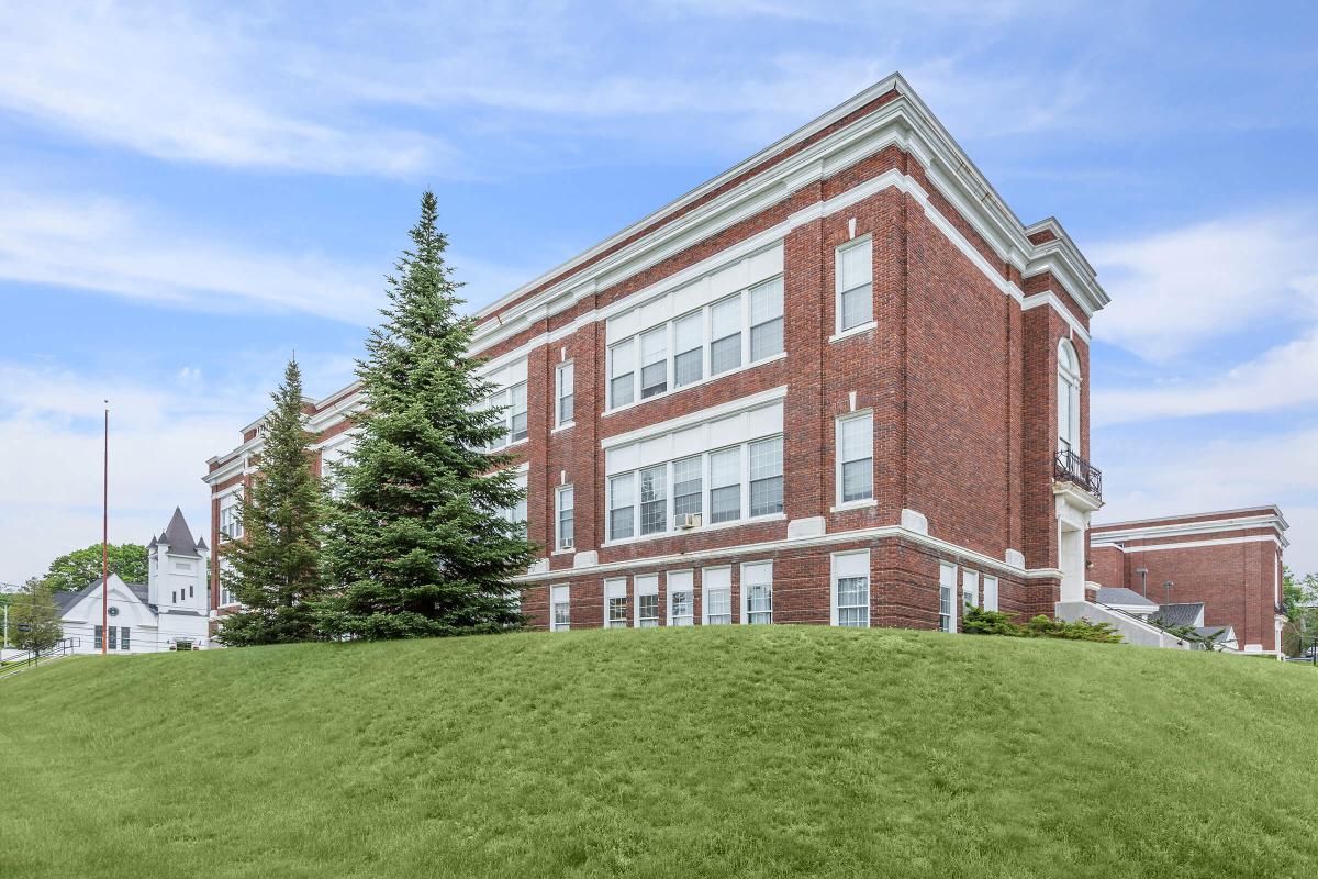 a large brick building with a grassy field