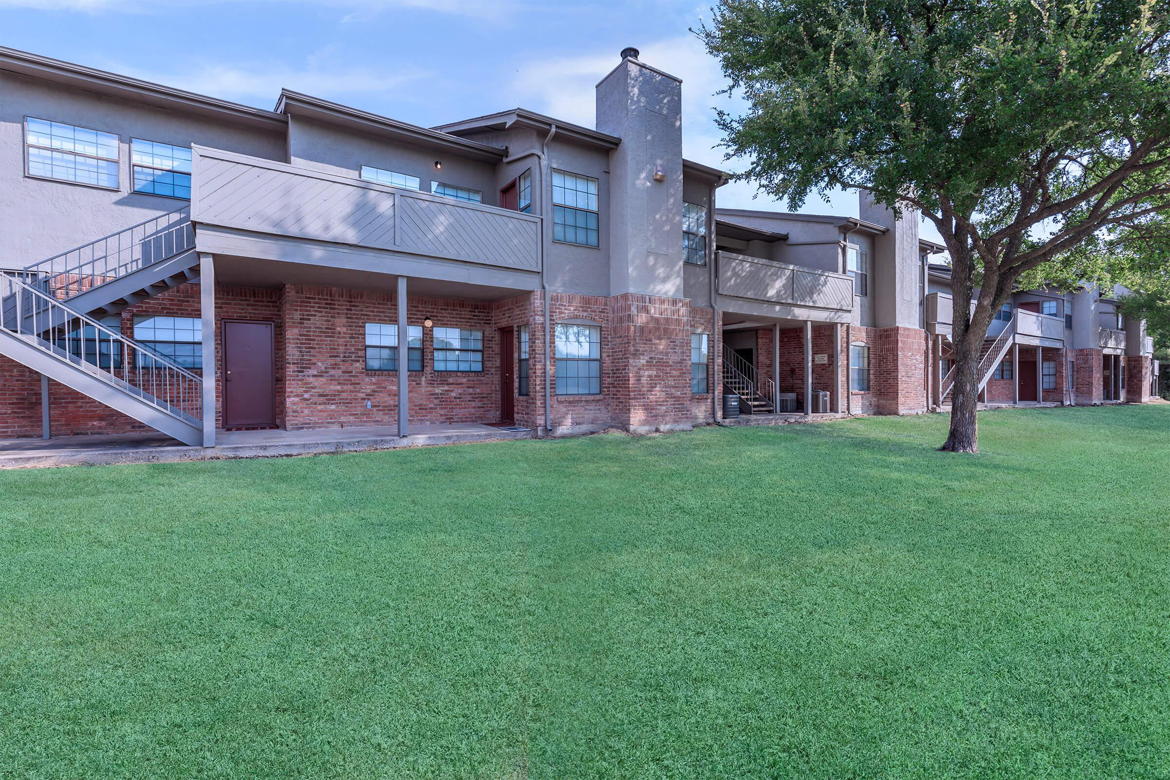 a large lawn in front of a brick building