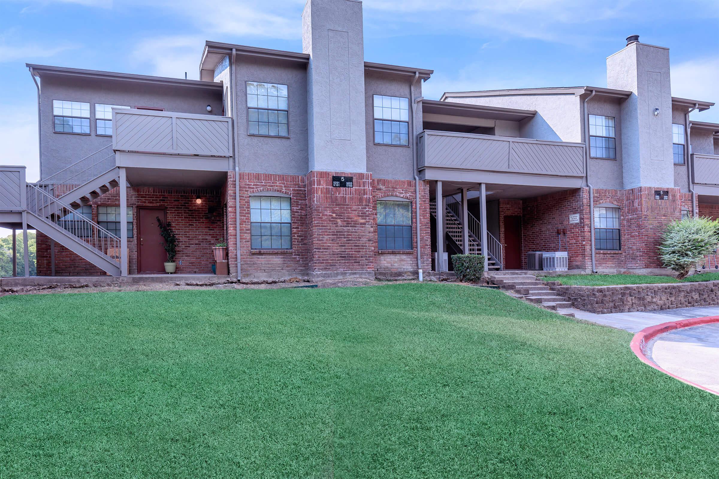 a large lawn in front of a brick building