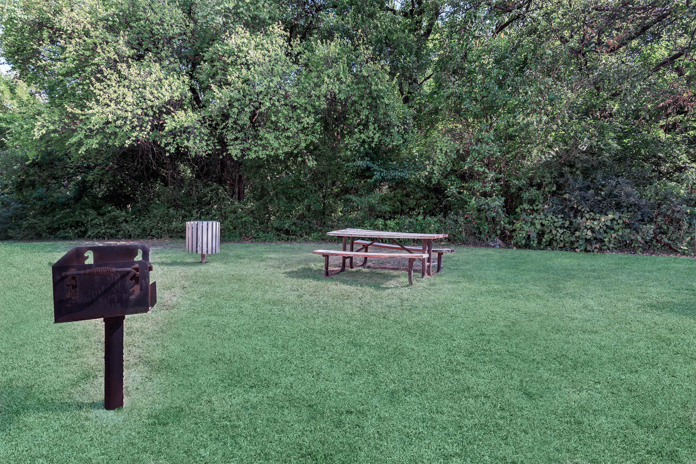 an empty park bench next to a green field
