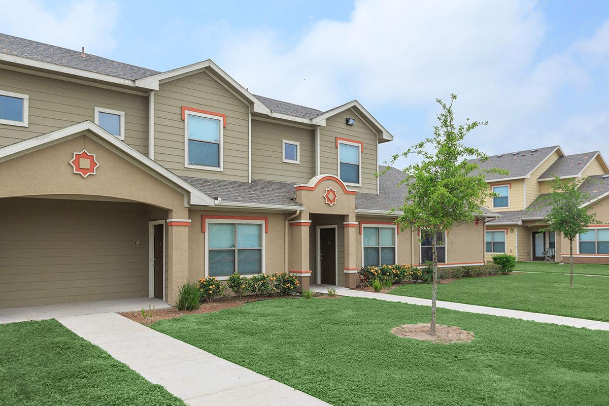 a house with a lawn in front of a brick building