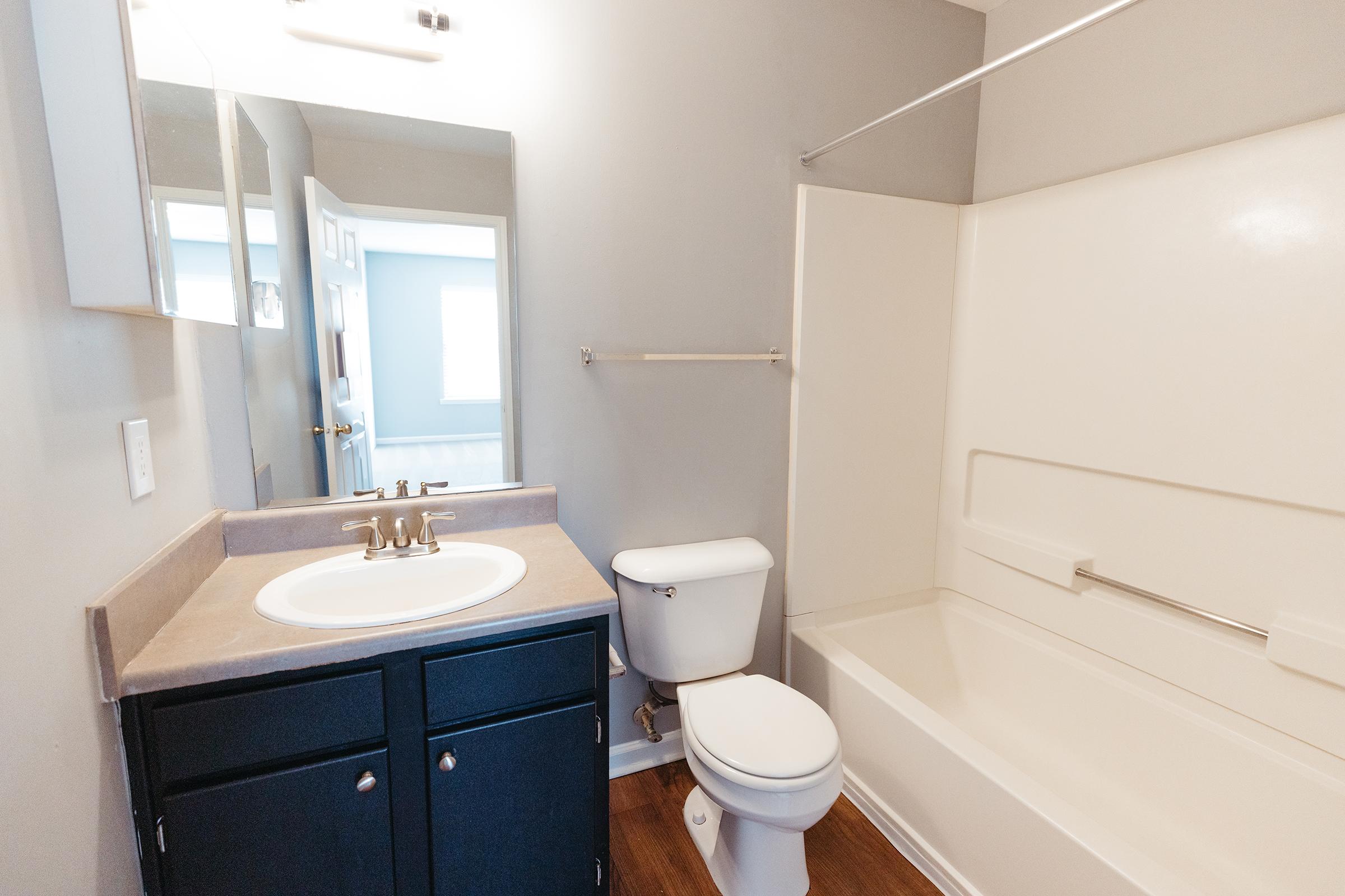 Bathroom with small single sink, toilet, and tub with shower.