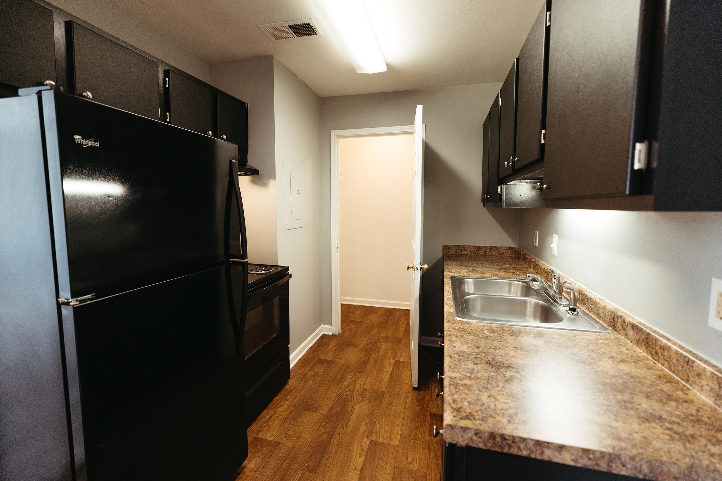 Long kitchen view with pantry door open.