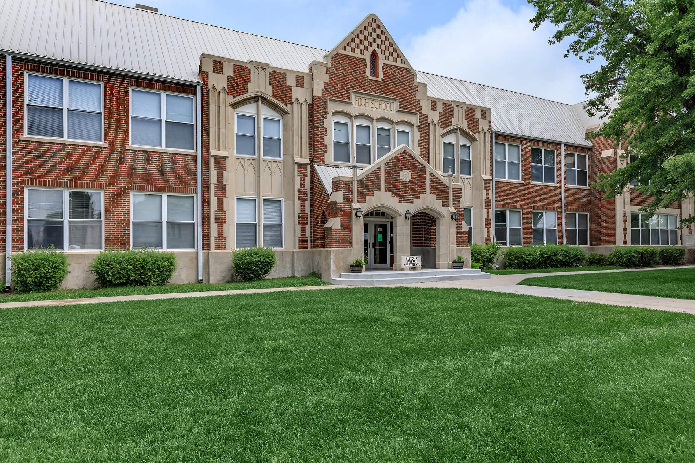 a large brick building with grass in front of a house