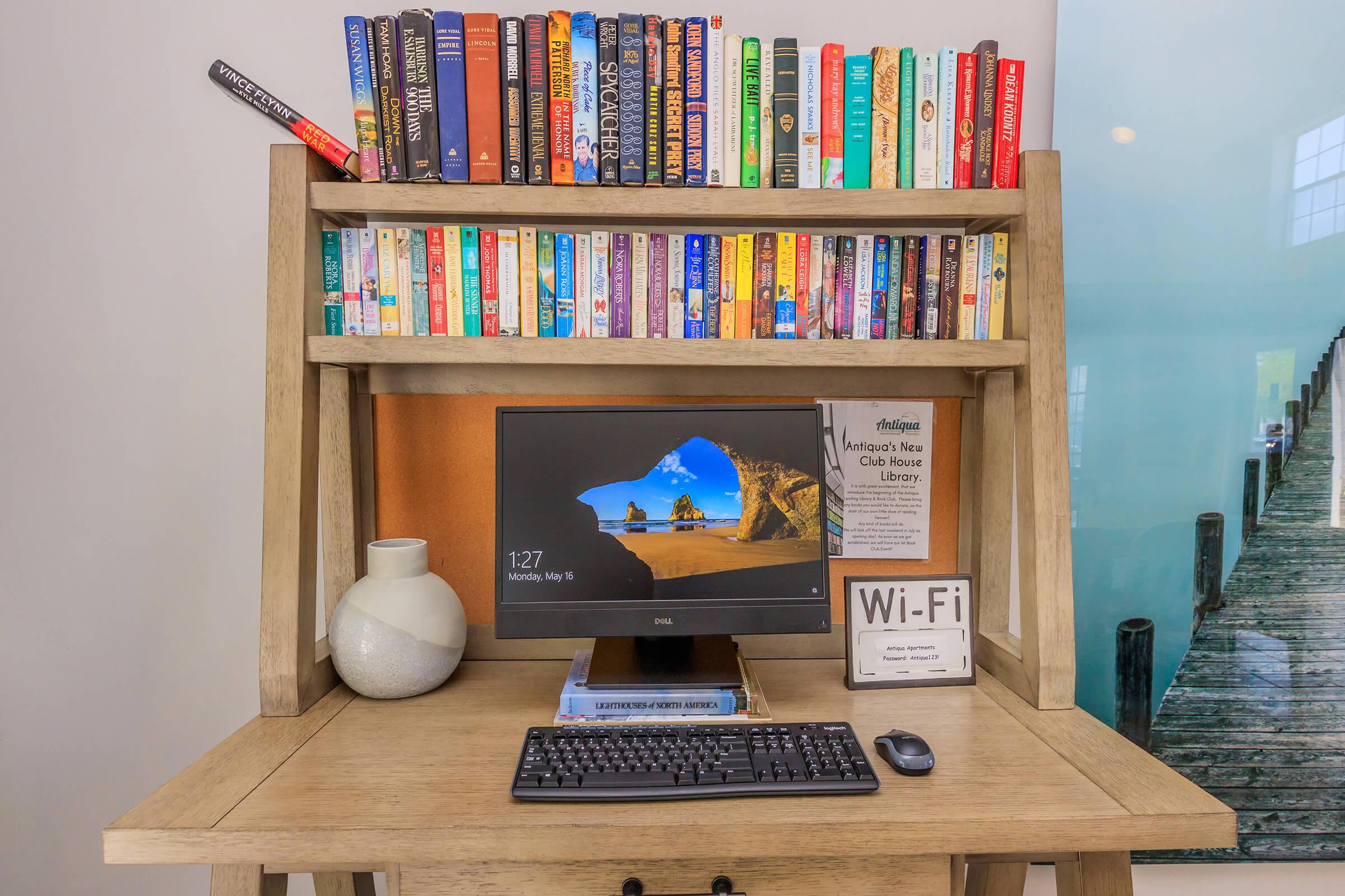 a desktop computer sitting on top of a wooden desk with a book shelf