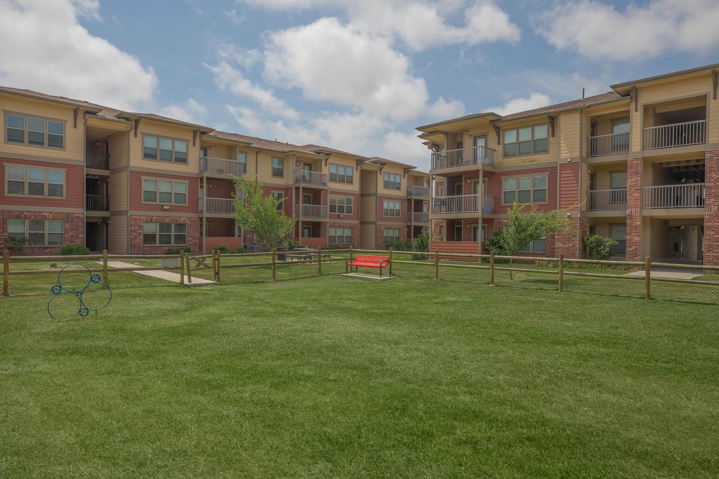 a large brick building with grass in front of a house