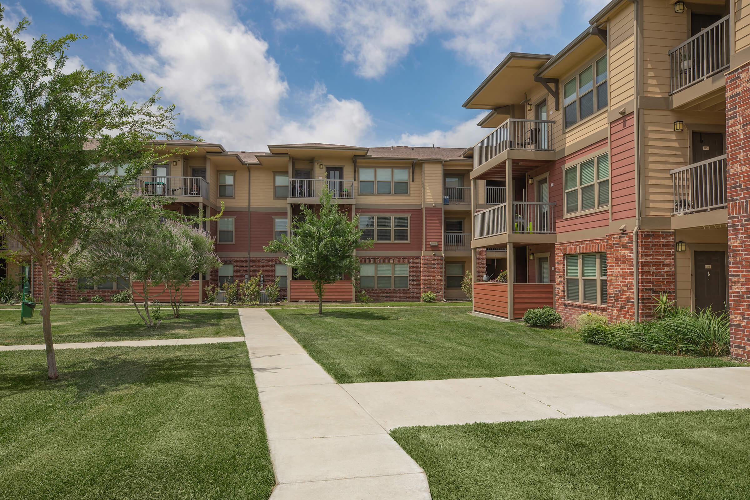 a large brick building with grass in front of a house