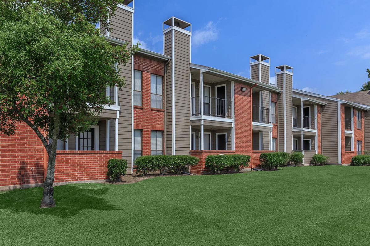 a large brick building with grass in front of a house