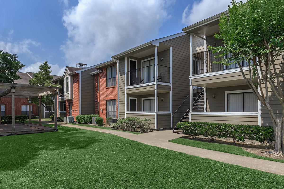 a house with a lawn in front of a brick building