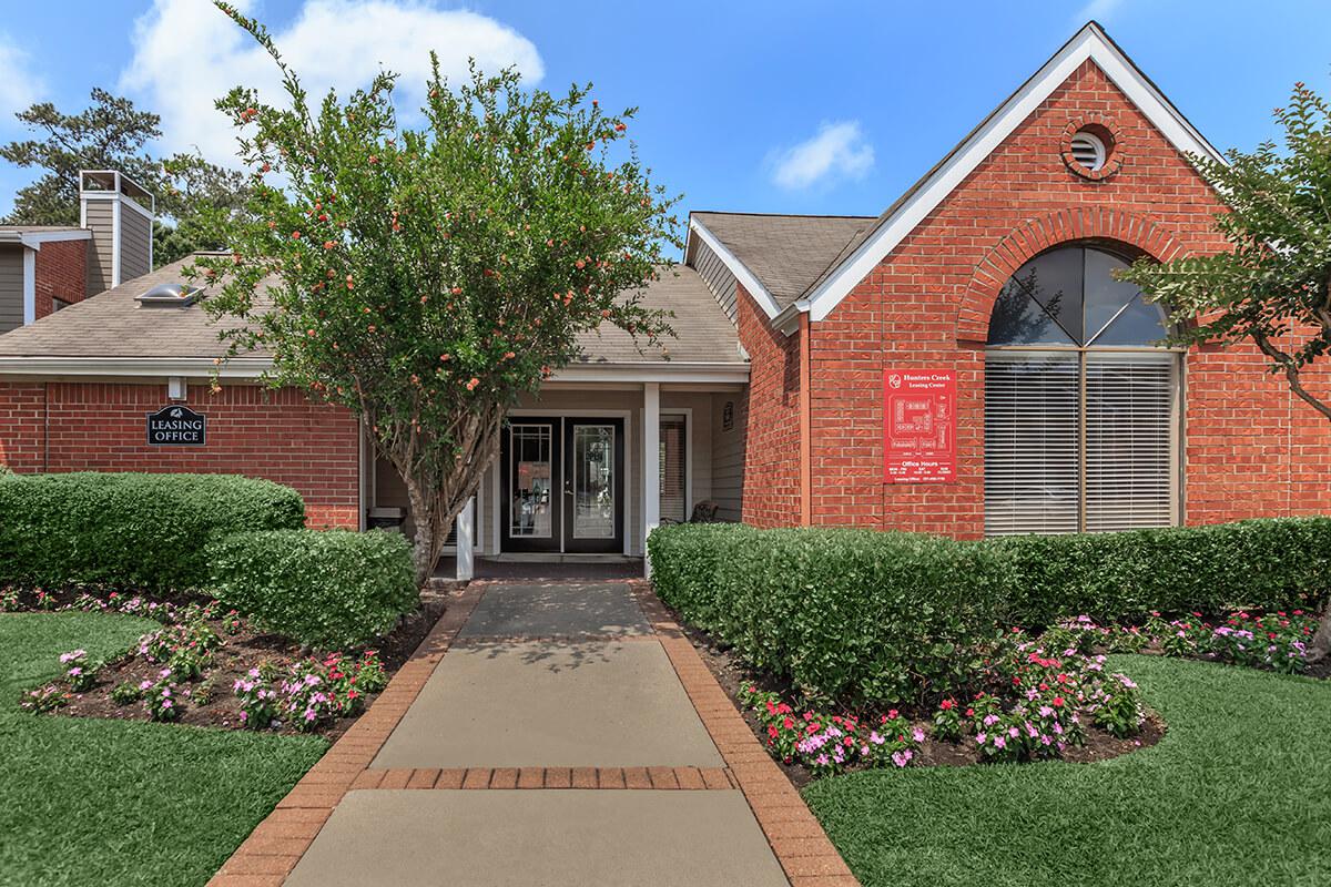 a large brick building with grass in front of a house