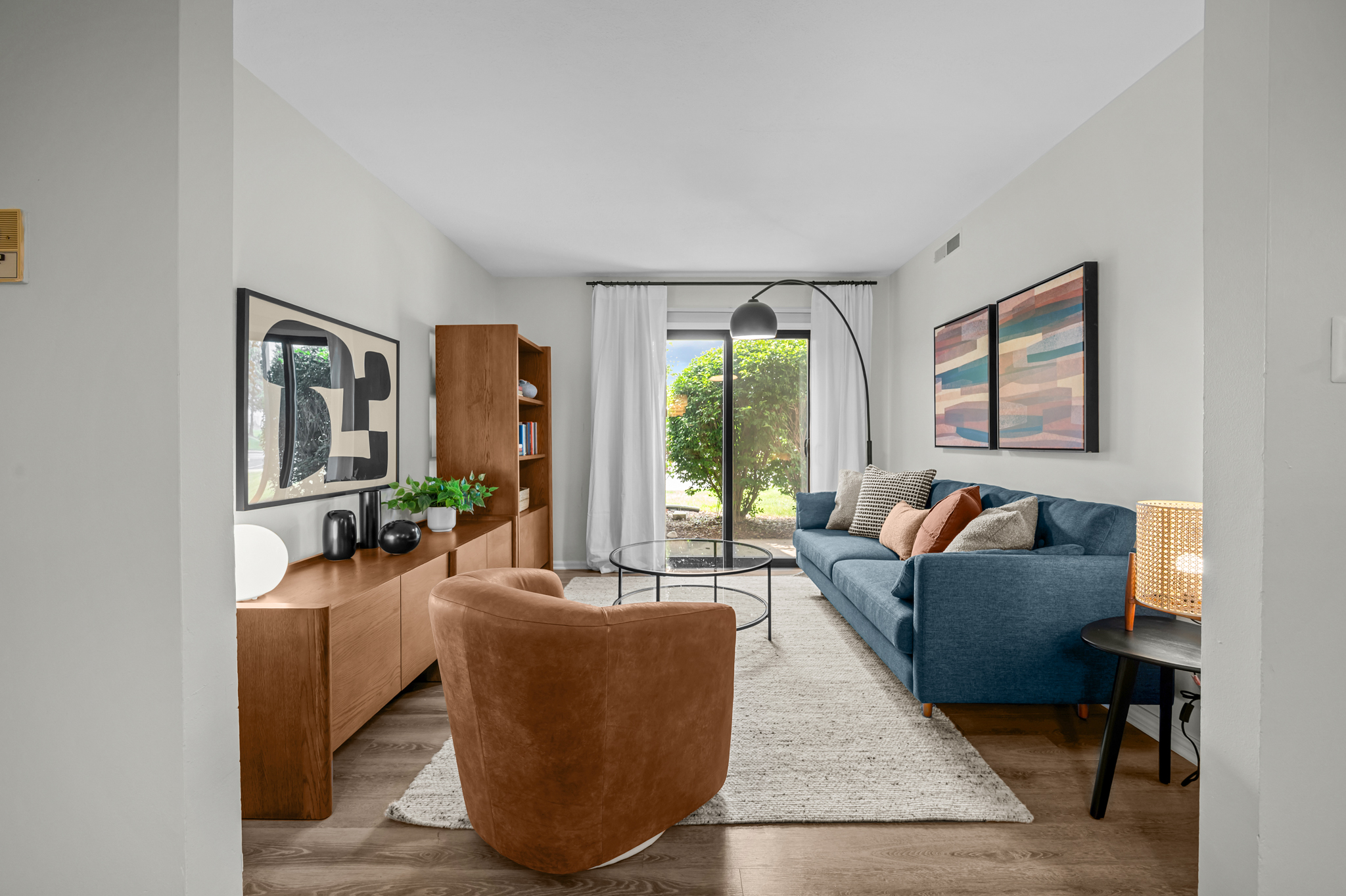 A living room with a blue couch and leather armchair at Port Crossing Apartments in Portage, Indiana.