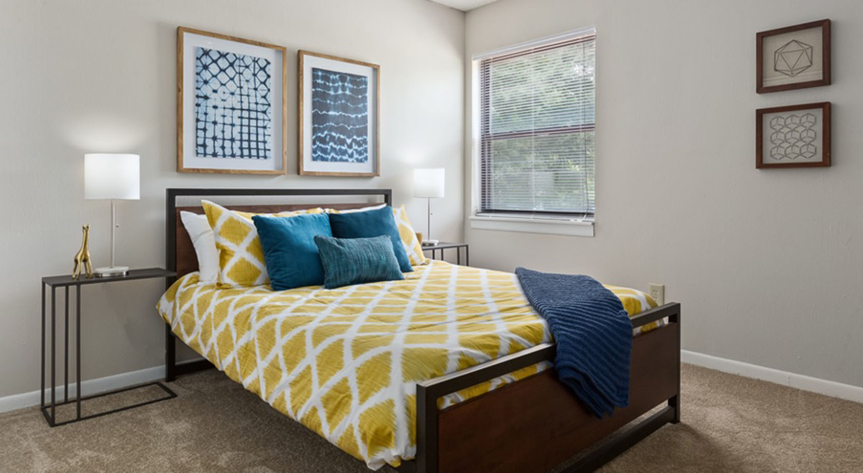 A bed with yellow bedding and blue blanket at Edgewater Village Apartments in Greensboro, NC