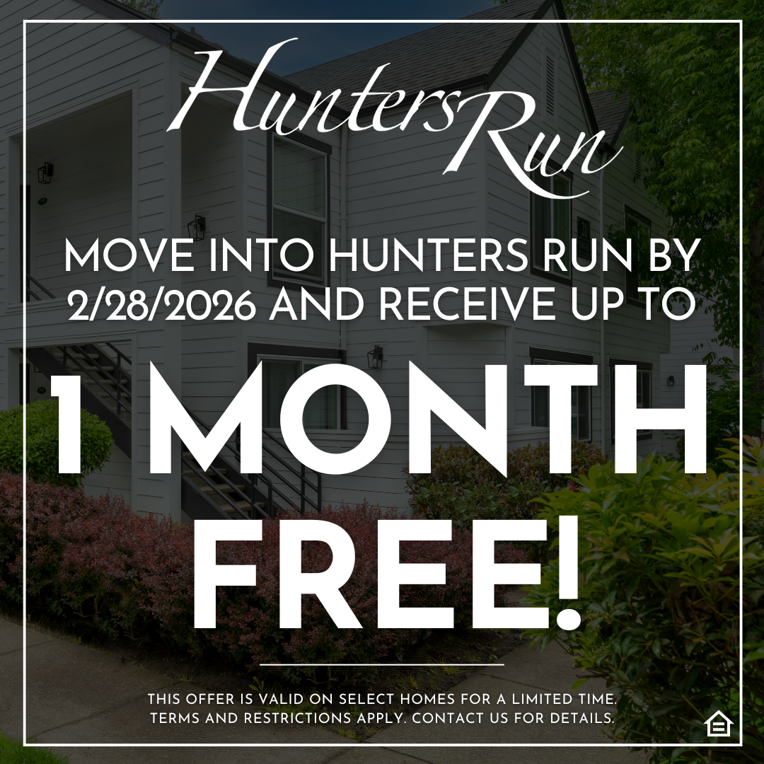 Promotional graphic featuring a background photo of a white apartment building with black trim, exterior stairs, and green landscaping. The 'Hunters Run' logo appears in white script at the top. Overlaid text reads, 'Move into Hunters Run by 2/28/2026 and receive up to,' followed by large, bold white text stating, '1 MONTH FREE!' Fine print at the bottom states, 'This offer is valid on select homes for a limited time. Terms and restrictions apply. Contact us for details,' alongside an Equal Housing Opportun