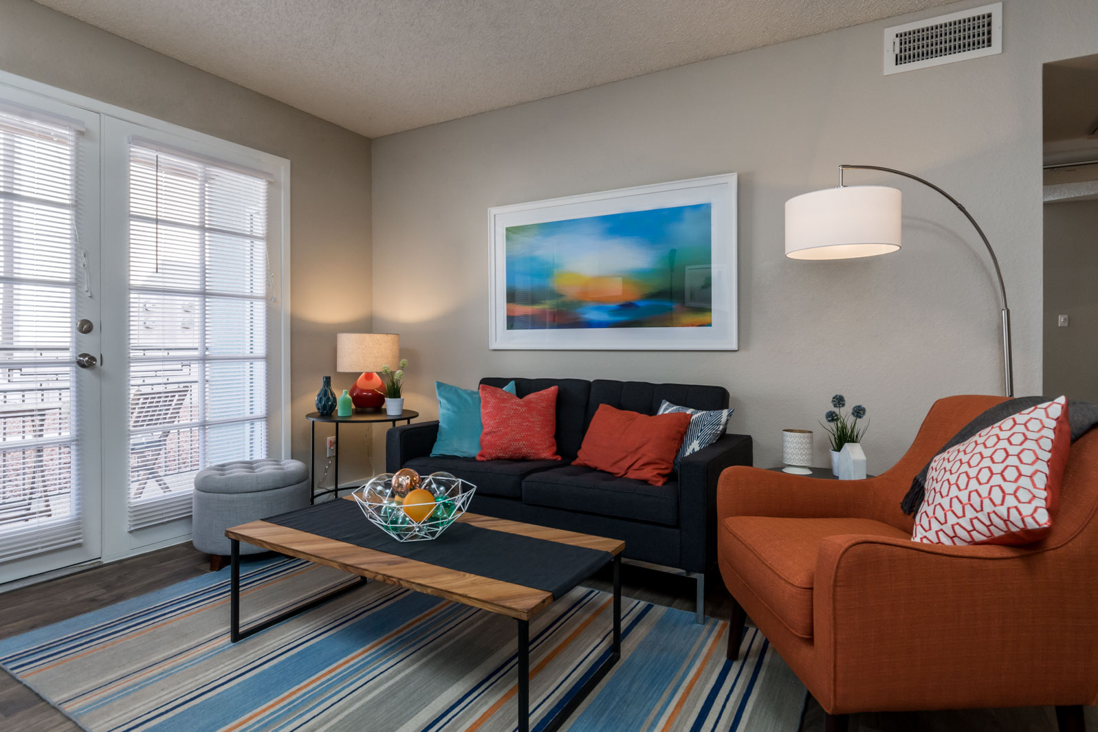 A living room with a couch and a painting on the wall at Azul Apartments in Phoenix, AZ