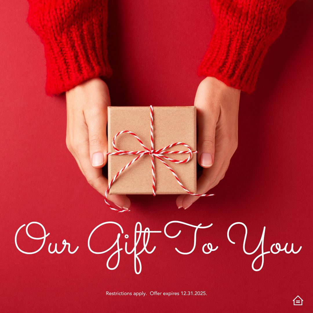 Hands holding a small gift wrapped in brown paper with red and white twine, set against a bright red background. The graphic reads “Our Gift To You” and notes that restrictions apply and the offer expires 12.31.2025. Equal housing opportunity.