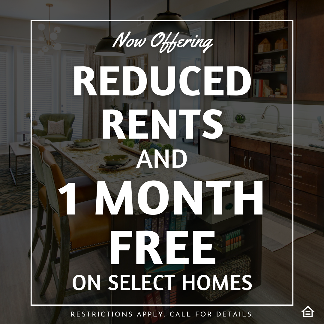 A promotional graphic overlaid on a photo of a modern apartment kitchen and living area. Large white text within a thin white border reads "Now Offering REDUCED RENTS AND 1 MONTH FREE ON SELECT HOMES". Below it, smaller text says "RESTRICTIONS APPLY. CALL FOR DETAILS.". The photo shows a kitchen island with two barstools, dark wood cabinets, and a living room with a sofa in the background. An Equal Housing Opportunity icon is in the bottom right corner.