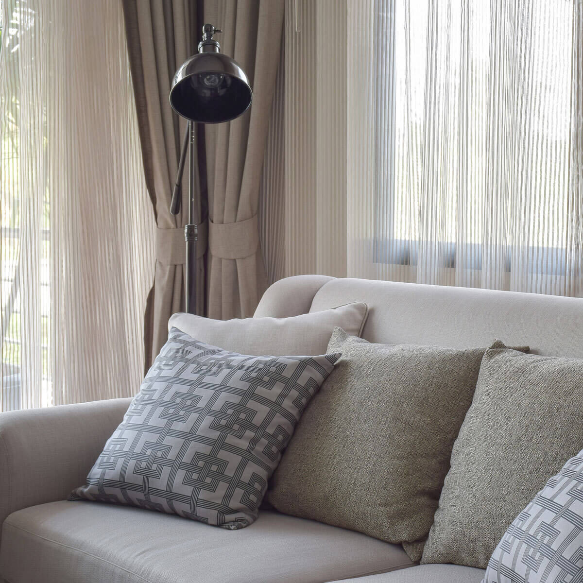 A white couch with decorative pillows and a modern lamp, perfect for a comfortable and inviting room.