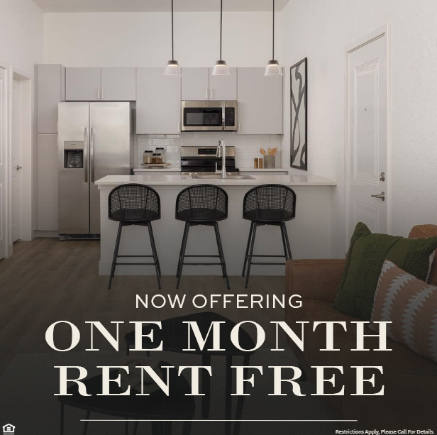 Modern apartment kitchen with stainless steel appliances, white cabinets, and three black barstools at an island. Promotional text overlay reads: “NOW OFFERING ONE MONTH RENT FREE.” Small print at the bottom says, “Restrictions Apply. Please Call For Details.”