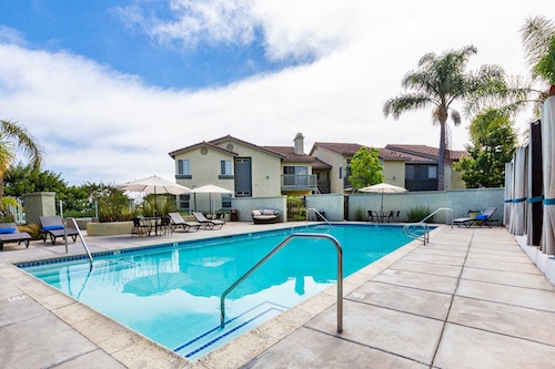 pool and sundeck area with apartment buildings in the background