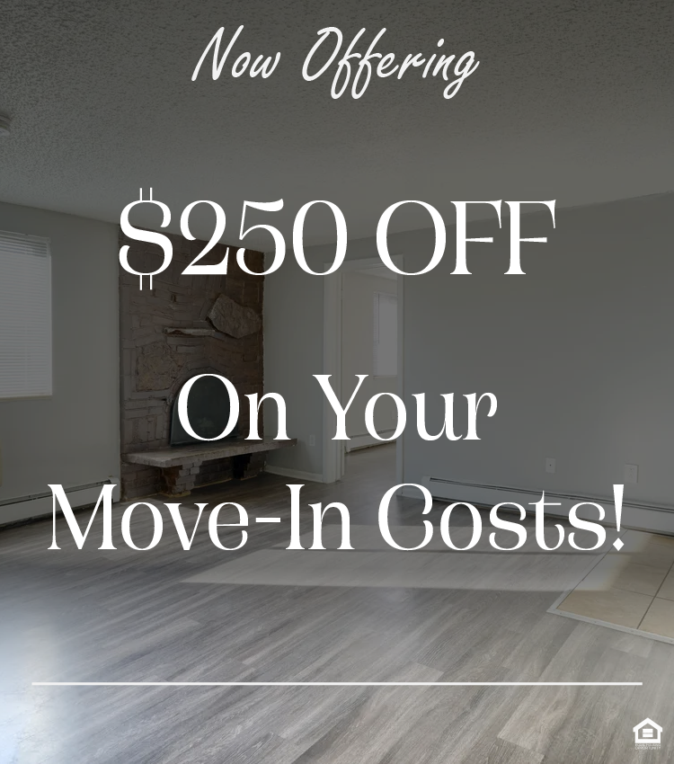 An empty living room with light gray walls, a window with blinds, an air conditioning unit, and a brown brick fireplace with a black screen. The floor is light hardwood with a tiled area visible. The text on the image says, "Now offering $250 off on your move-in costs"