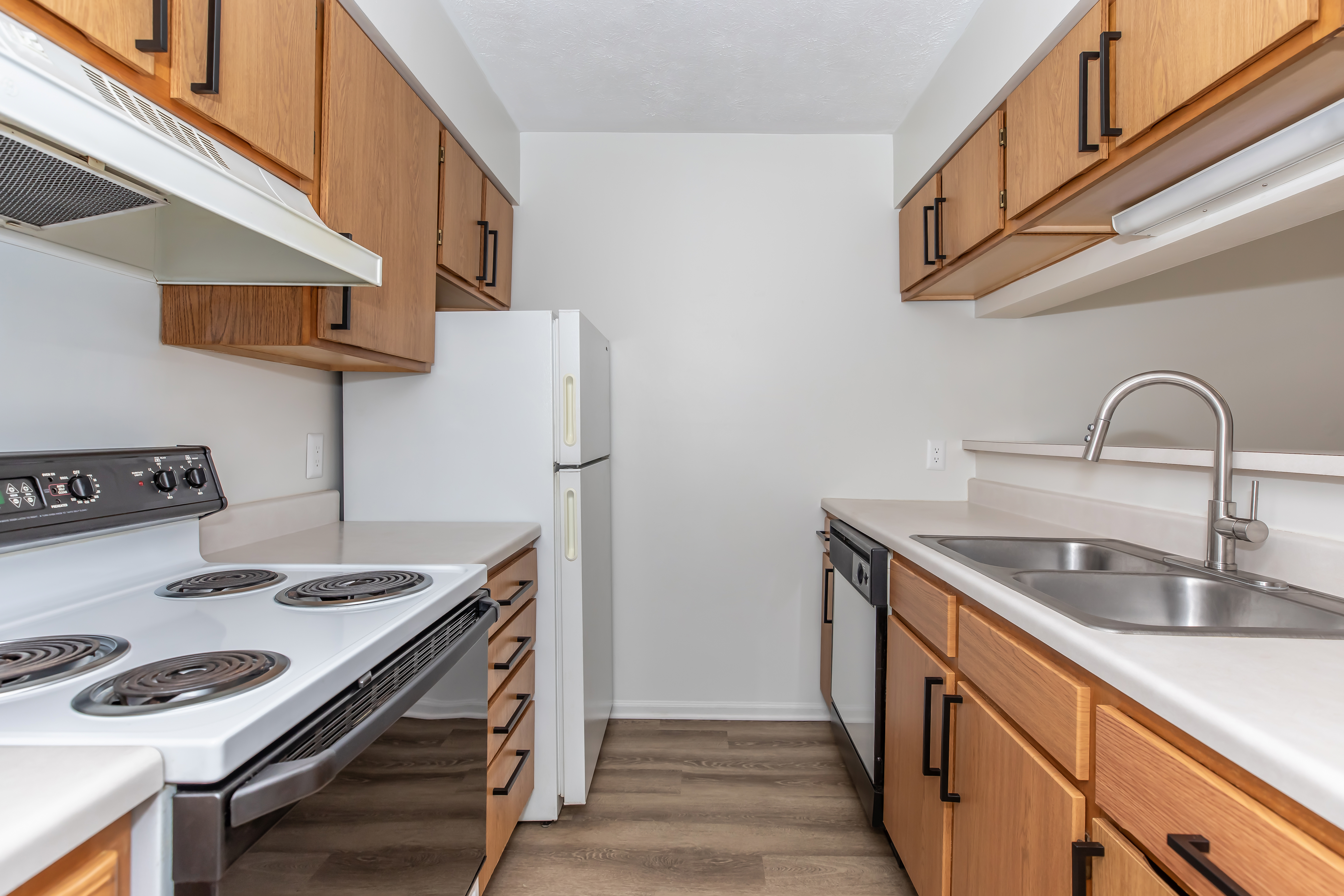 A kitchen with white appliances and wooden cabinets at Port Crossing Apartments in Portage, Indiana