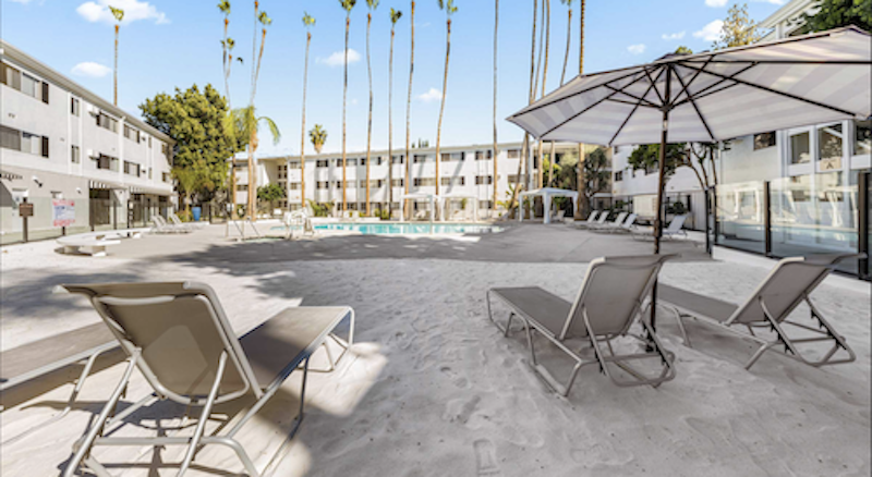 patio area with pool and palm trees and apartment buildings surrounding the area
