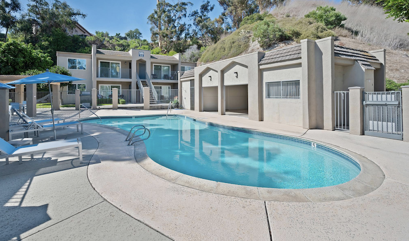 swimming pool with lounge chairs and apartments in the background