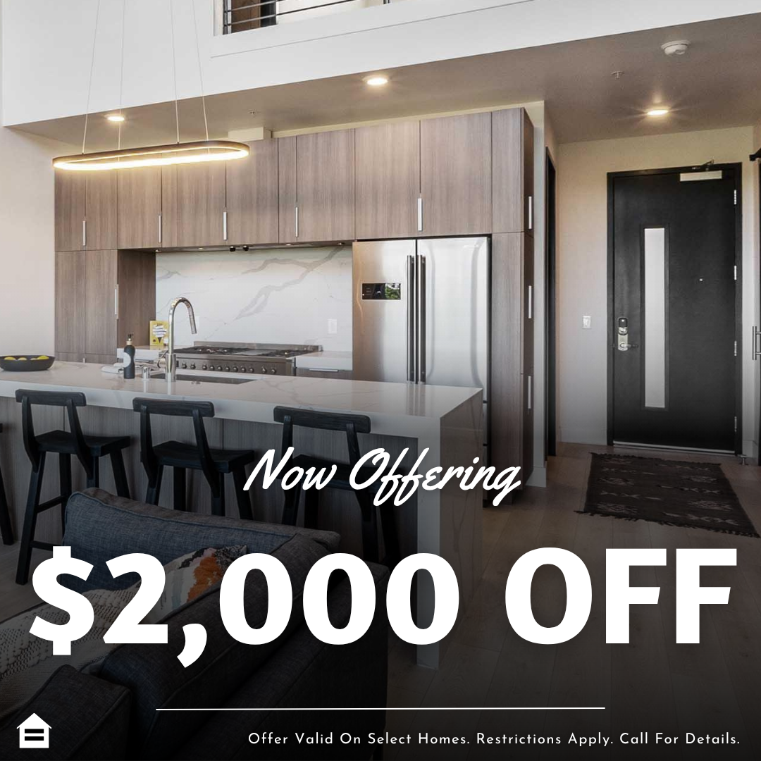A promotional graphic featuring a background photo of a modern, open-concept kitchen and living area with wood cabinets, a large island, and stainless steel appliances. Text overlaid on the lower half reads "Now Offering" in a script font, followed by a large, bold "$2,000 OFF". A disclaimer at the bottom states, "Offer Valid On Select Homes. Restrictions Apply. Call For Details." alongside an Equal Housing Opportunity logo.