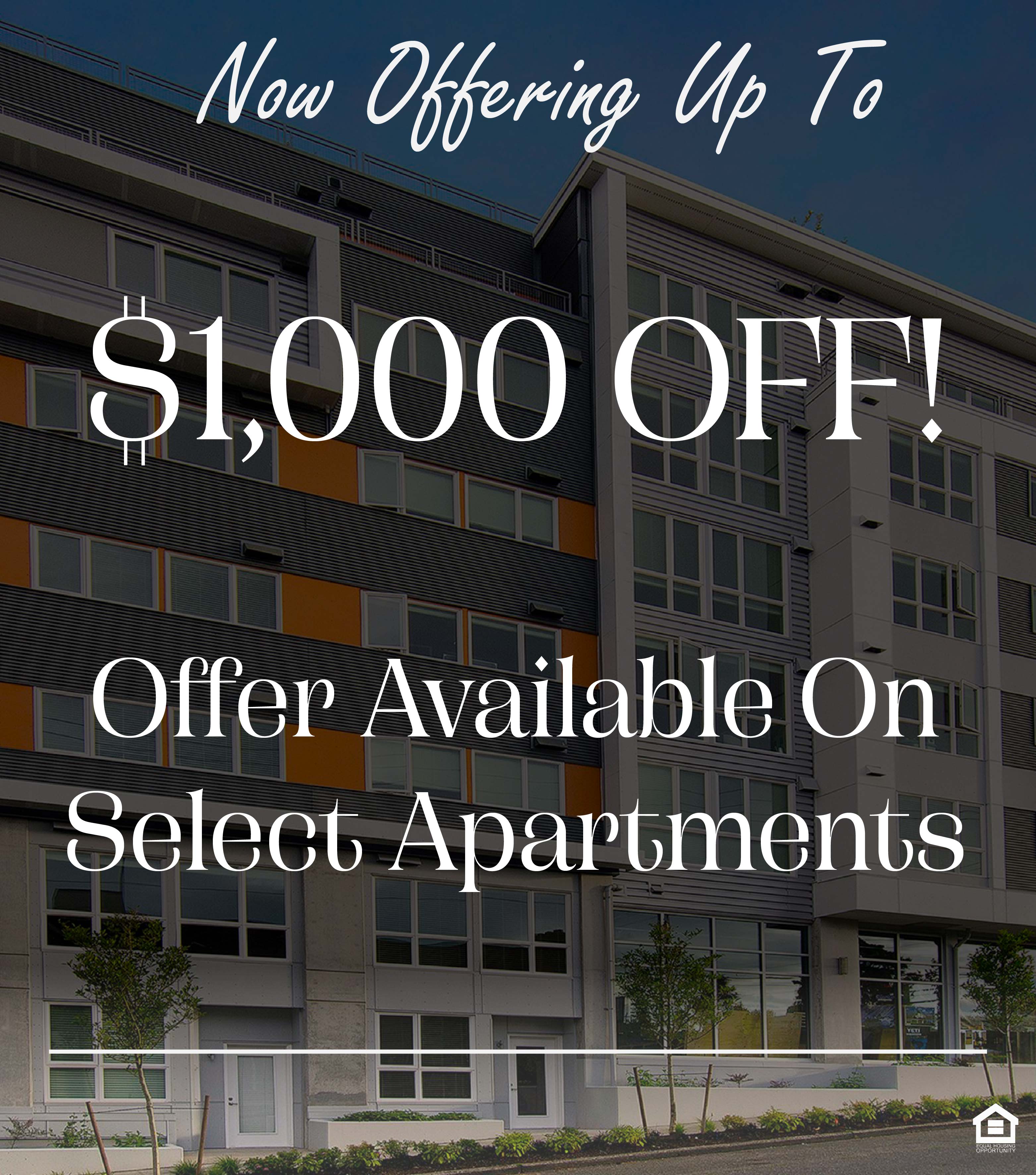 Modern multi-story building with a sleek exterior featuring a mix of gray and orange accents. Large windows dominate the facade, and the entrance is marked by a prominent sign reading "42." Surrounding the building are small trees and landscaping, set against a clear blue sky. The text on the image says, "Now offering up to $1,000 off! Offer available on select apartments."