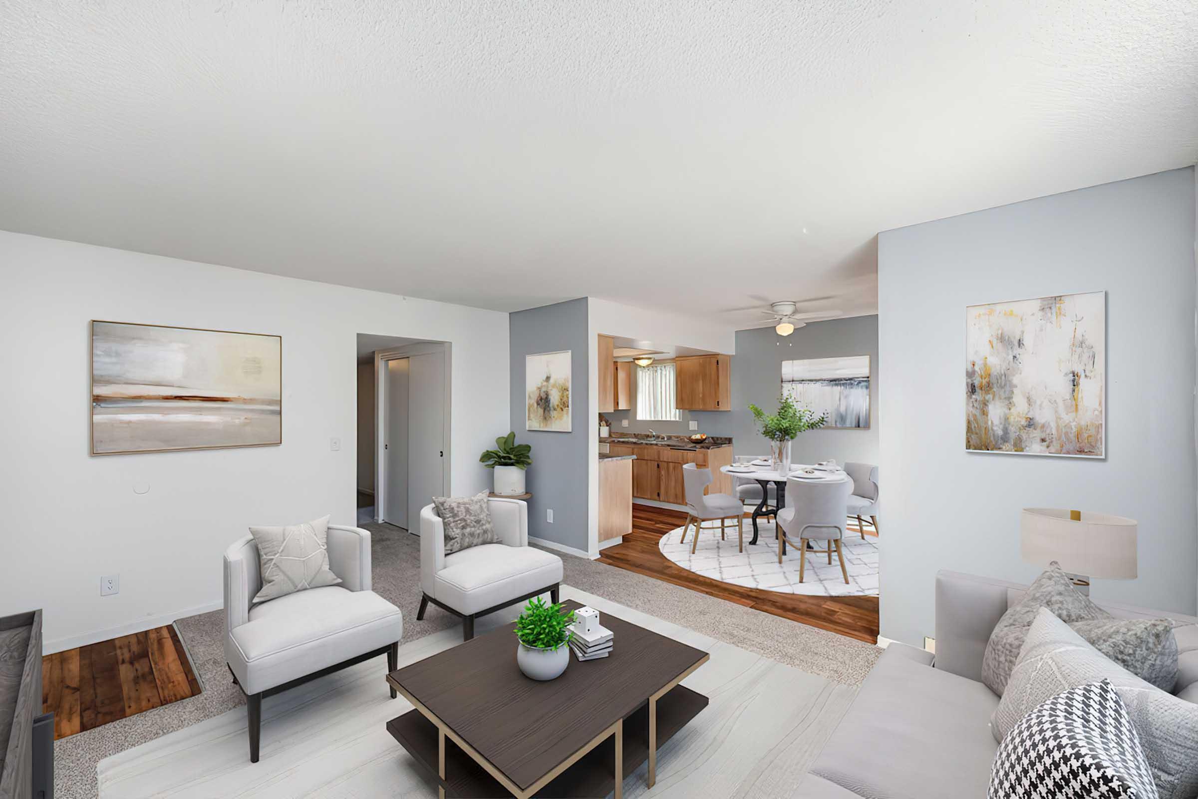 living room dining room and kitchen with two chairs and coffee table wood style plank flooring wood cabinets and granite counters