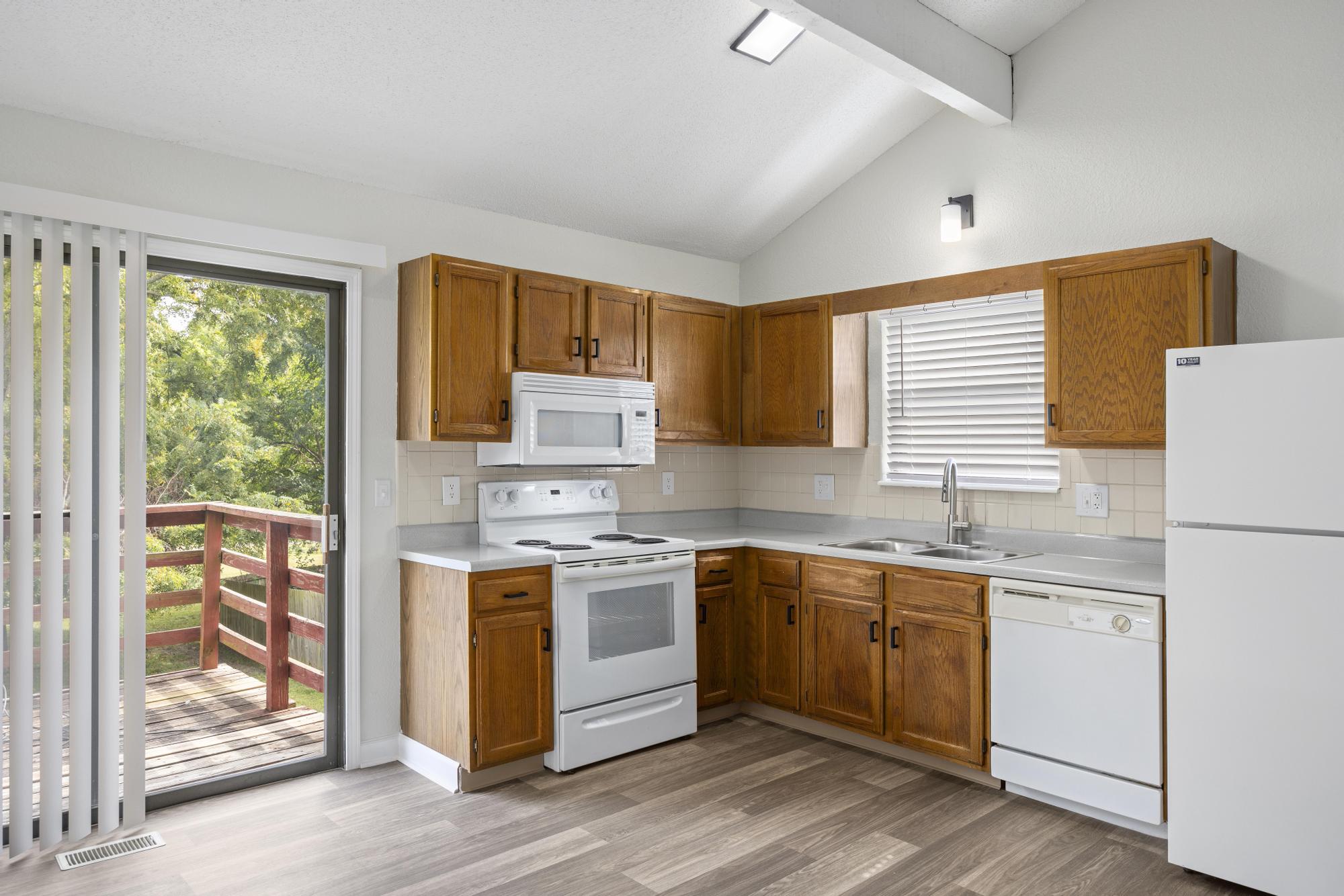 A kitchen with white appliances and wooden cabinetry at Ramsgate Apartments and Townhomes in Olathe, Kansas