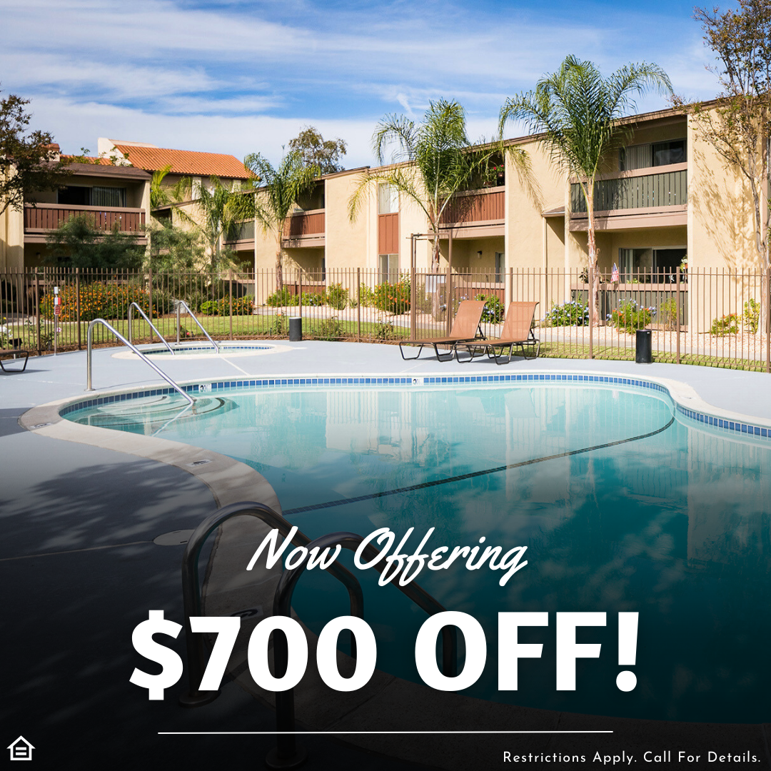 a pool surrounded by a fence and a few lounger chairs in an apartment community on a sunny day with palm trees. overlaying text reading now offering $700 off! restrictions apply. call for details.