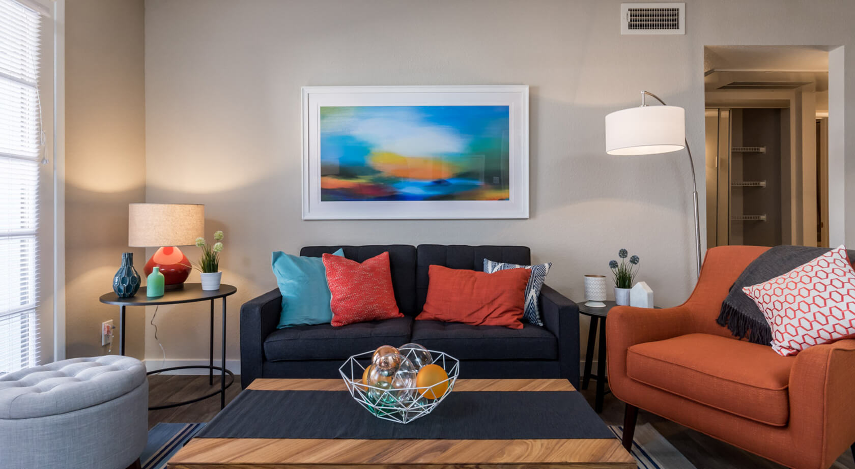 A living room with a couch and a painting on the wall at Azul Apartments in Phoenix, AZ