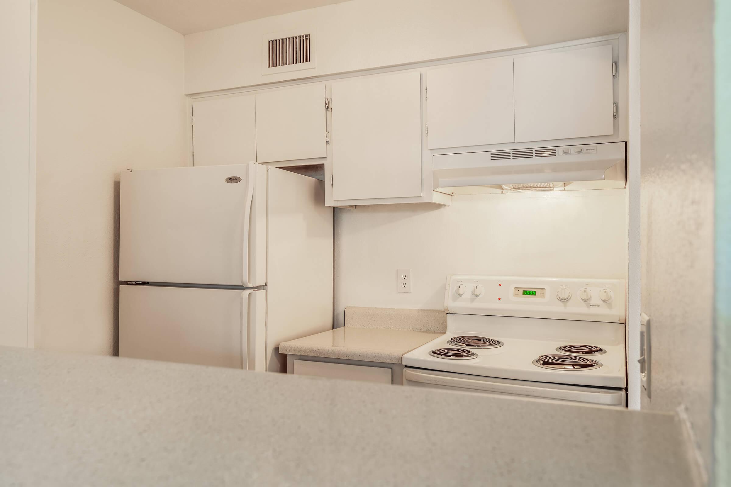 All white kitchen with white cabinets, white appliances, and grey countertops