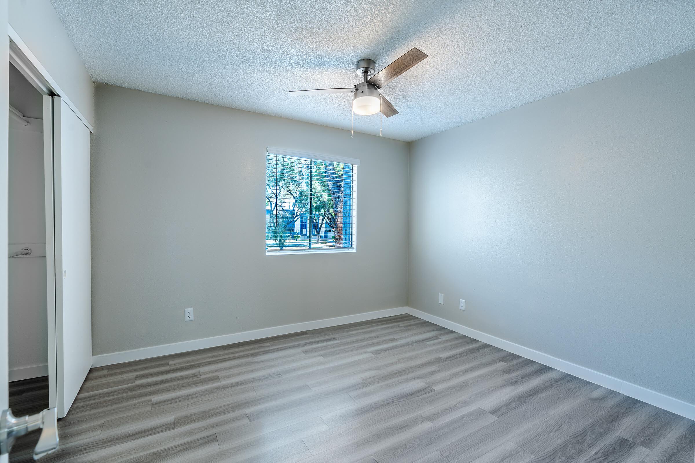 Large modern renovated bedroom with large window, closet, and ceiling fan