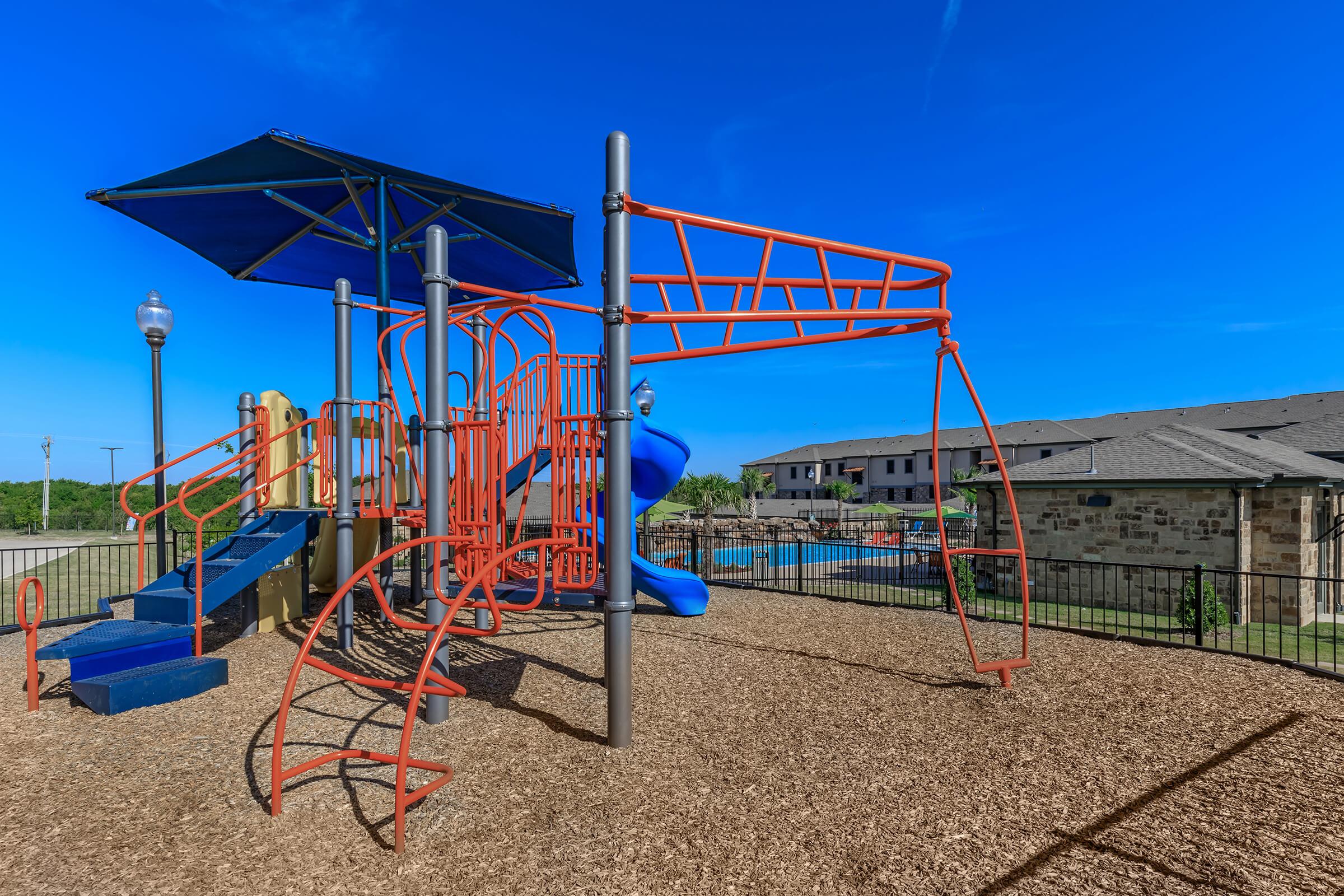 a playground with a blue umbrella